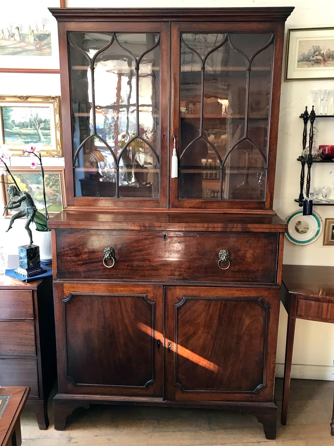 A high quality 18th century Georgian mahogany secrétaire bookcase / cupboard with two glazed doors with adjustable sliding shelves. The pullout / pull-out secretaire drawer with solid brass lion handles incloses a fitted interior with pigeon holes