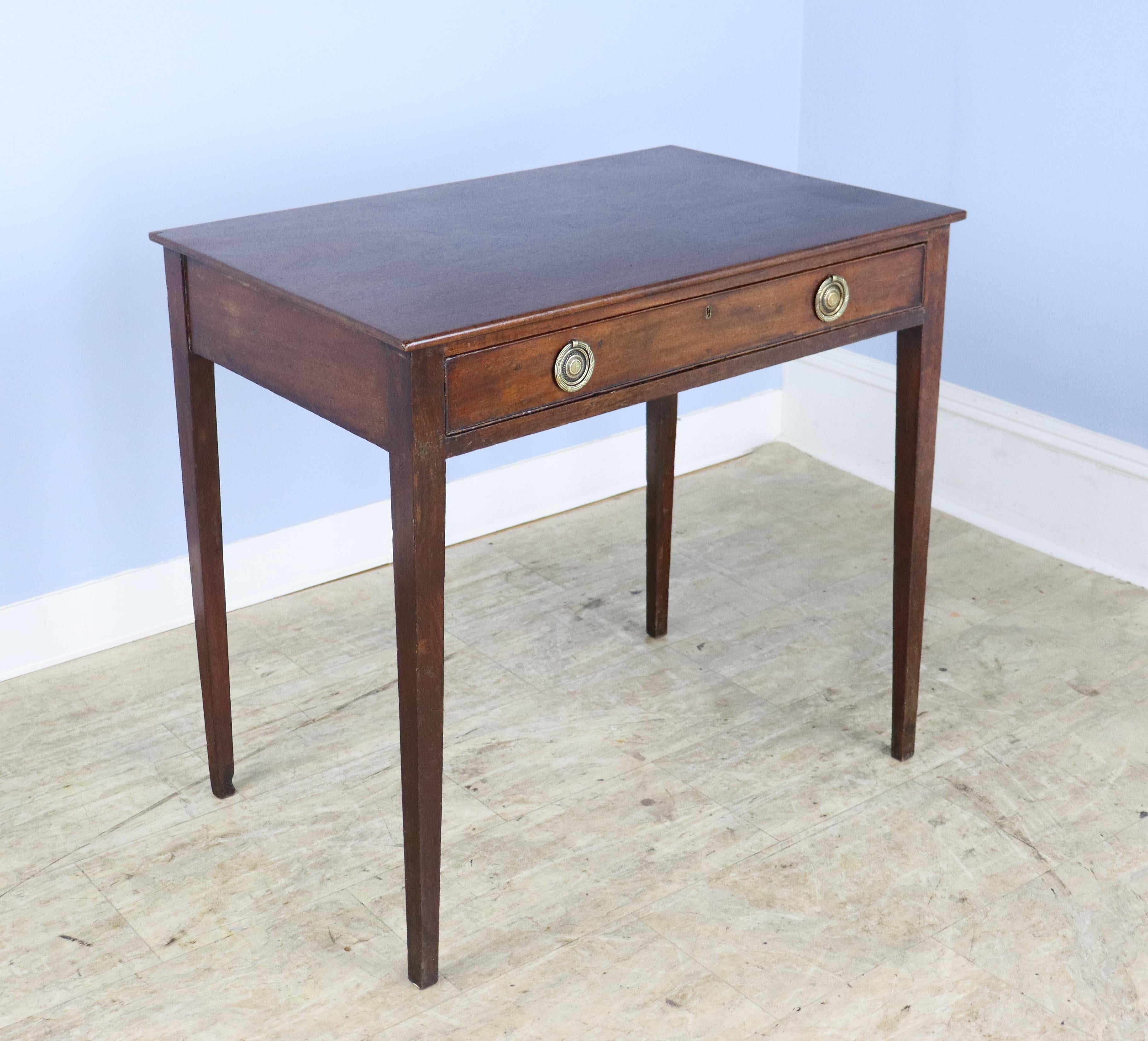 An antique occasional table from England. Classic Georgian shape. Mahogany with a rich grain and patina. One wide drawer with classic brass handles under carved edge. Would make a suitable lamp table. Top has been lightly refinished. but there is