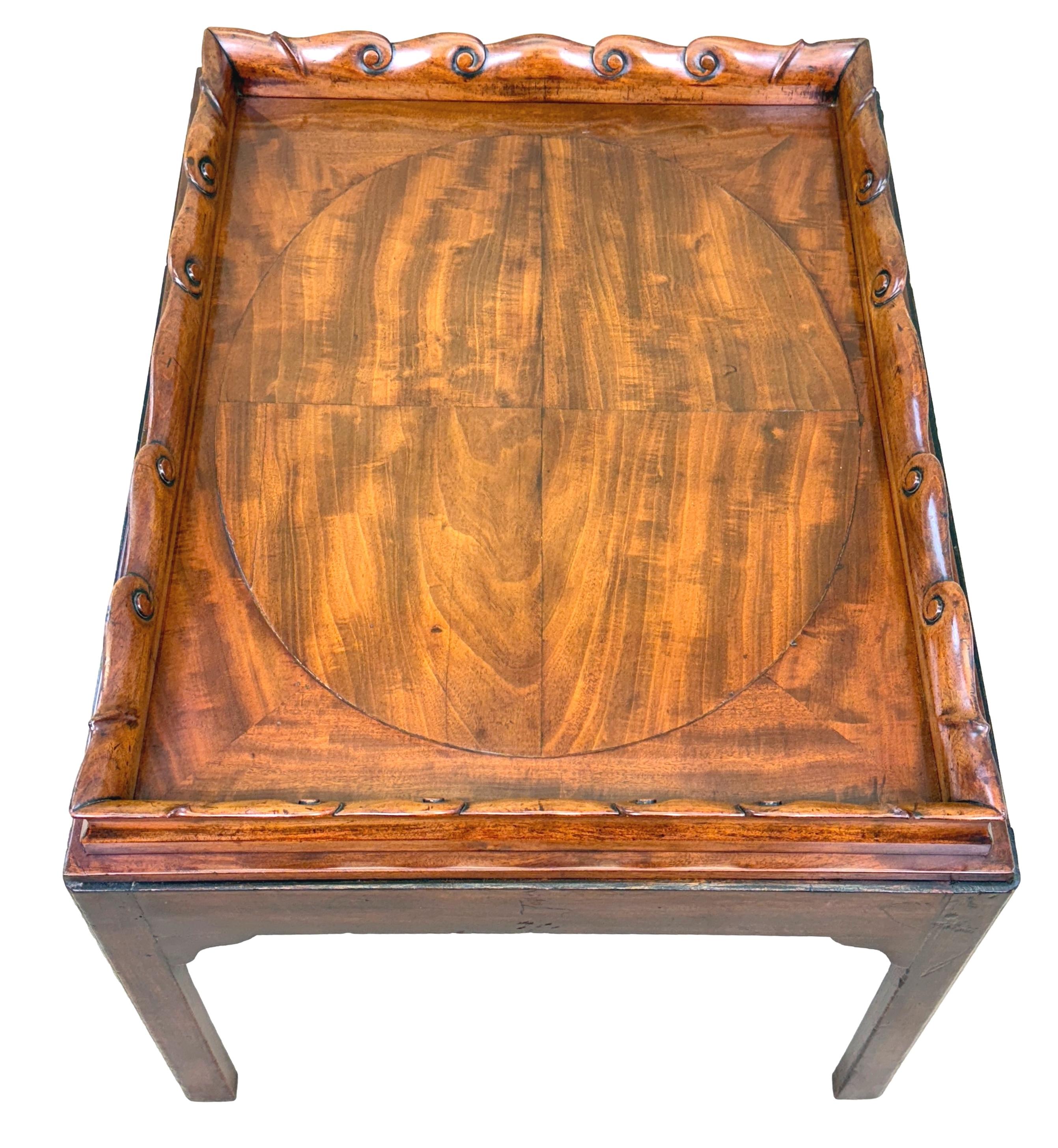 Rara bandeja rectangular de caoba de la época de Jorge III, de magnífico color y pátina, con un atractivo panel ovalado segmentado en la parte superior, muy bien modelado, con una elegante galería ondulada festoneada en el borde, sobre una base de