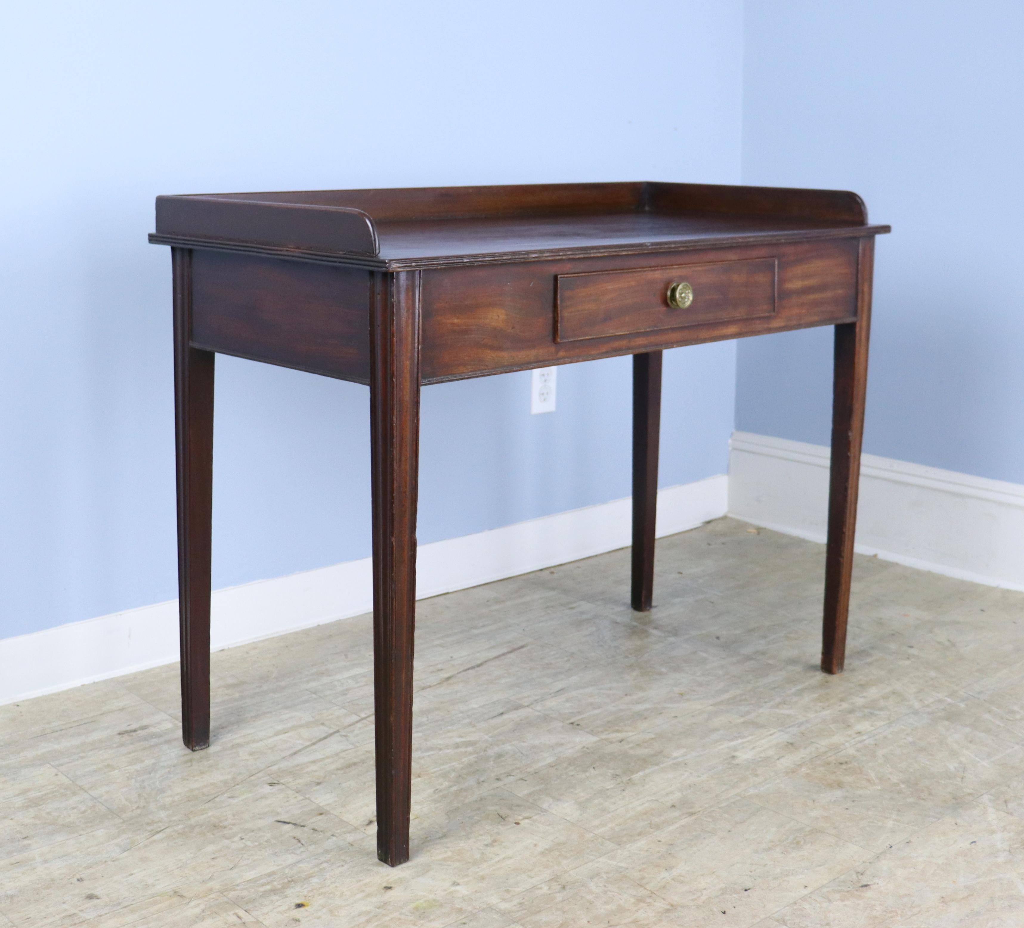 An 18th Century mahogany writing table with galleried back, reeded edge on the top, and a single wide drawer.  There is a bit of old wear on the top, highlighted in image #10.  In good sturdy condition.  No wobbling.  The height measurement is for