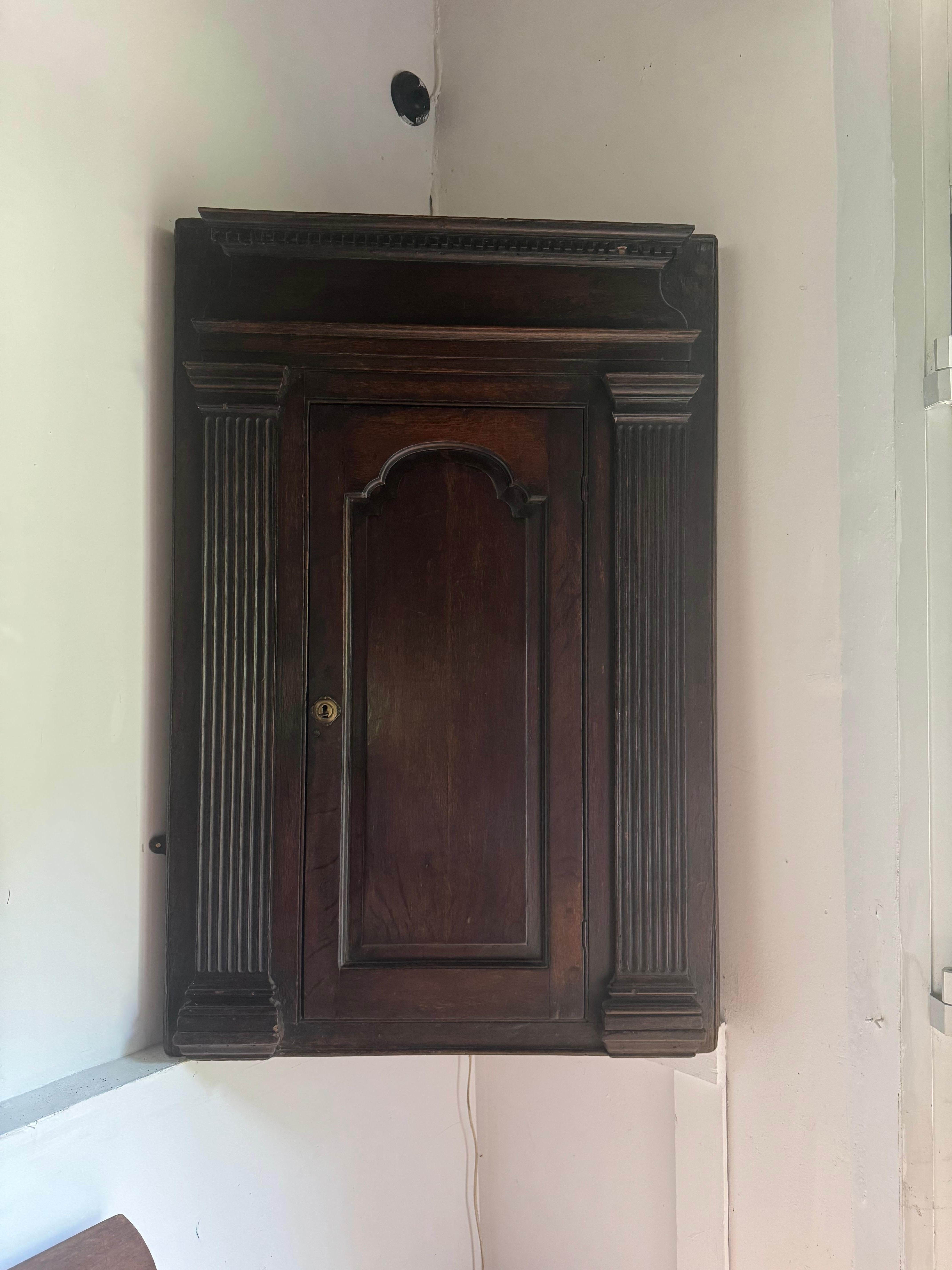Armadio angolare in quercia scura ben patinata della fine del XVIII secolo in stile georgiano. Vernice originale all'interno e cerniere. Serratura sostituita. Lievi danni dovuti all'età dell'articolo.