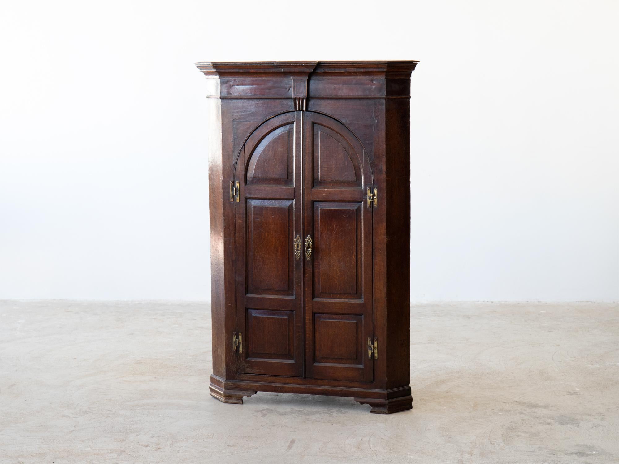 A freestanding Georgian oak corner cupboard.

English, circa 1770.

A charming gothic influence to the arched panelled doors, opening to reveal three shaped shelves above two small drawers.

In excellent order. Superb colour and patina to the aged