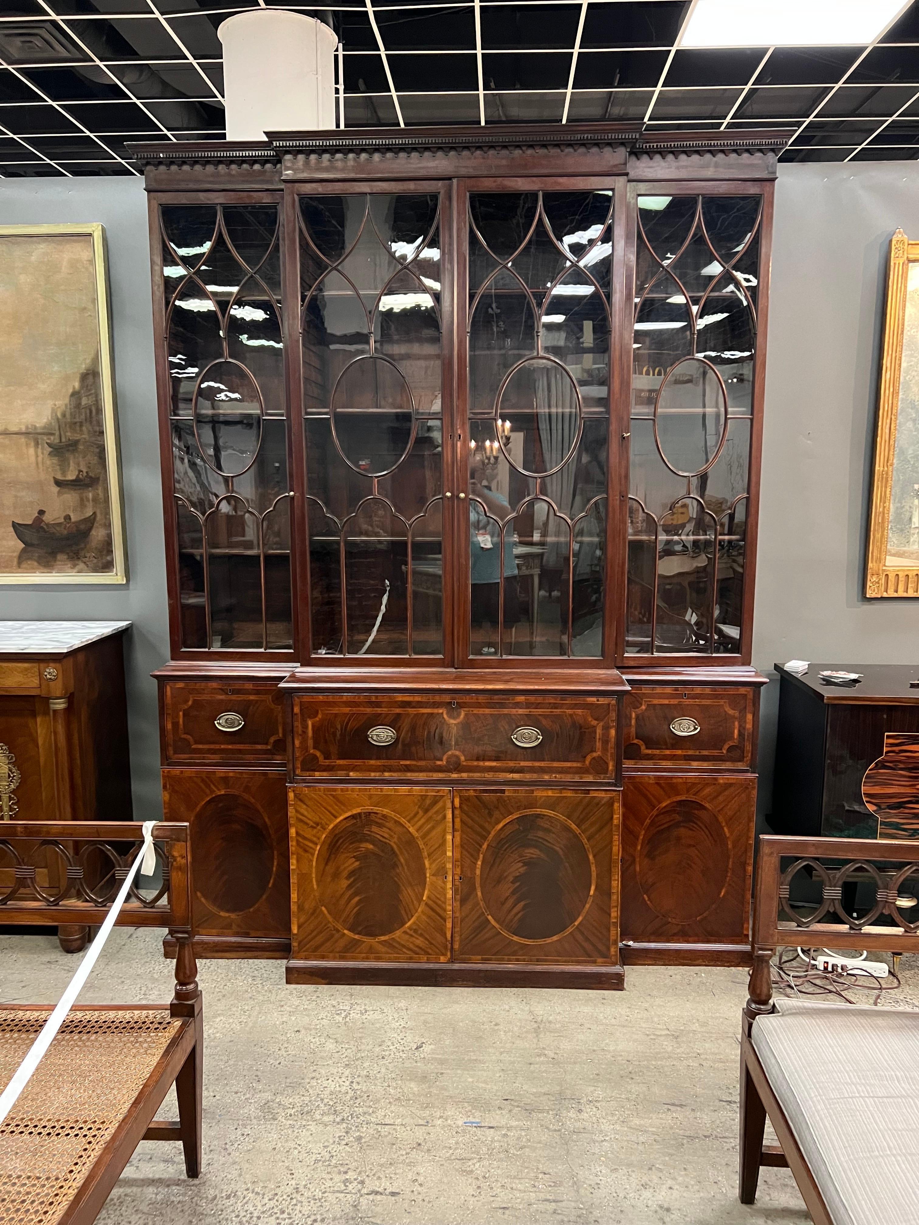 Fine 18th century Georgian period mahogany breakfront bookcase with secretary desk. The piece features glazed bookcase doors over an inlaid case with drawers behind the left and right oval inlaid doors. The central secretary desk has a leather top
