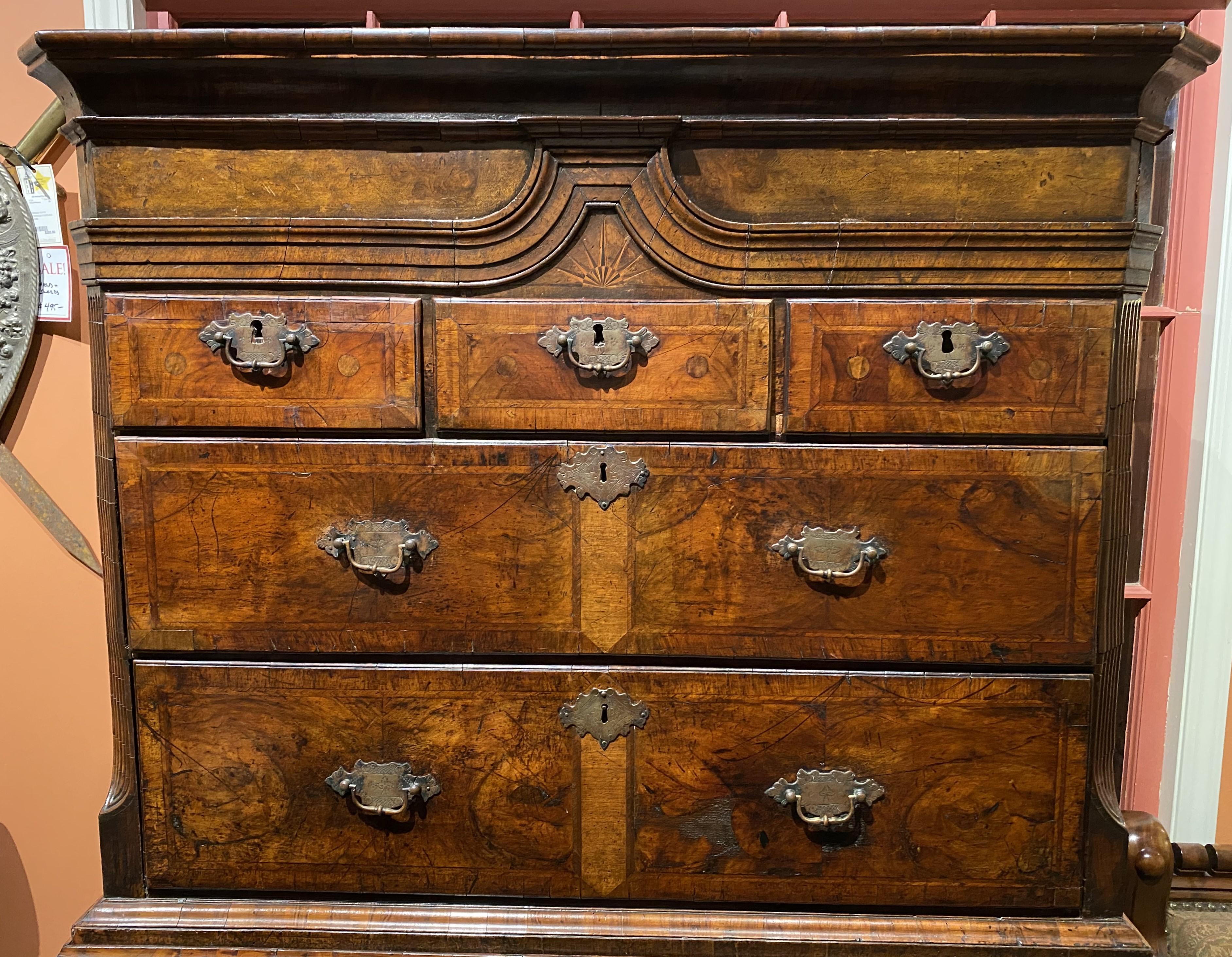 An impressive English Georgian walnut tall chest on stand, with a molded cornice, surmounting an upper case with a center small radial star inlay decoration over three fitted drawers over two long drawers, all with crossbanded veneers, flanked by