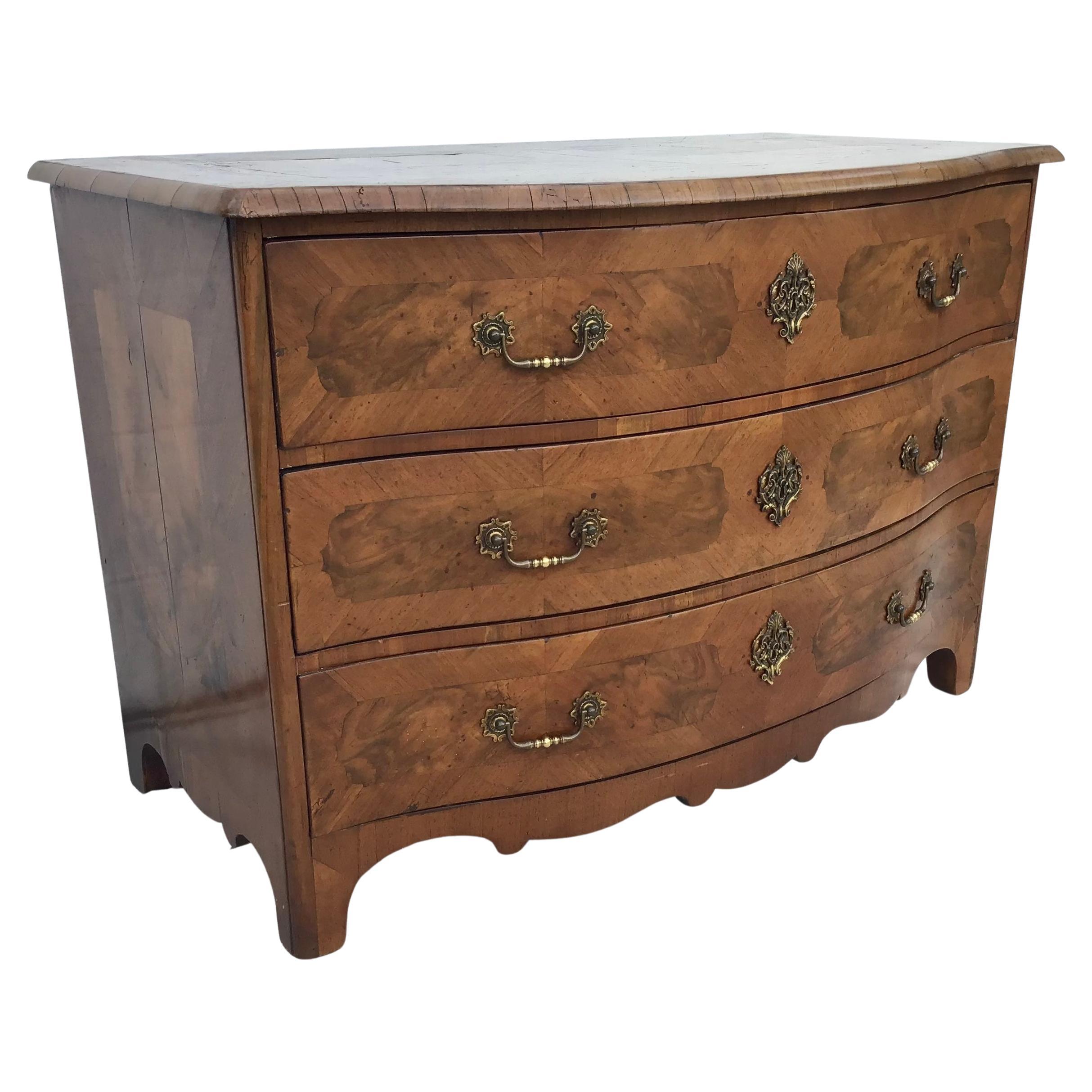 18th Century German Baroque Commode or chest of drawers with curved top front edge, three stacked dovetailed drawers with brass pulls, serpentine front and top, supported on block feet. Inlaid sides, top and drawers. Brass hardware and original iron