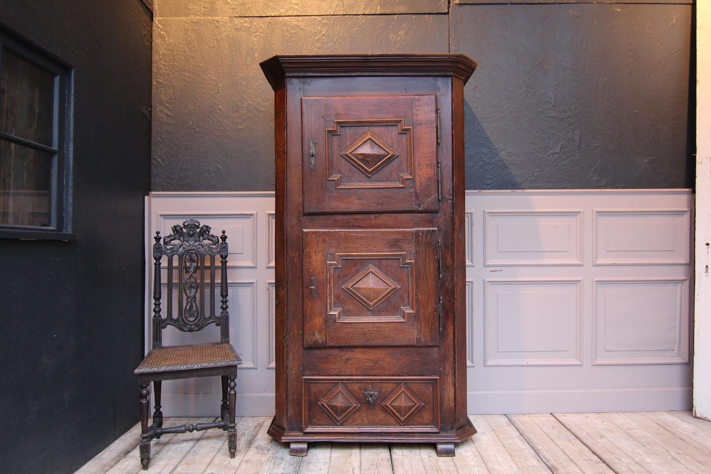 German baroque cupboard. Probably Westphalia, around 1760.

Narrow two-door oak corpus on sled feet with sloping pilaster strips, plinth drawer and profiled cornice. The two doors are each hung on 2 large handmade iron fittings.

Dimensions: