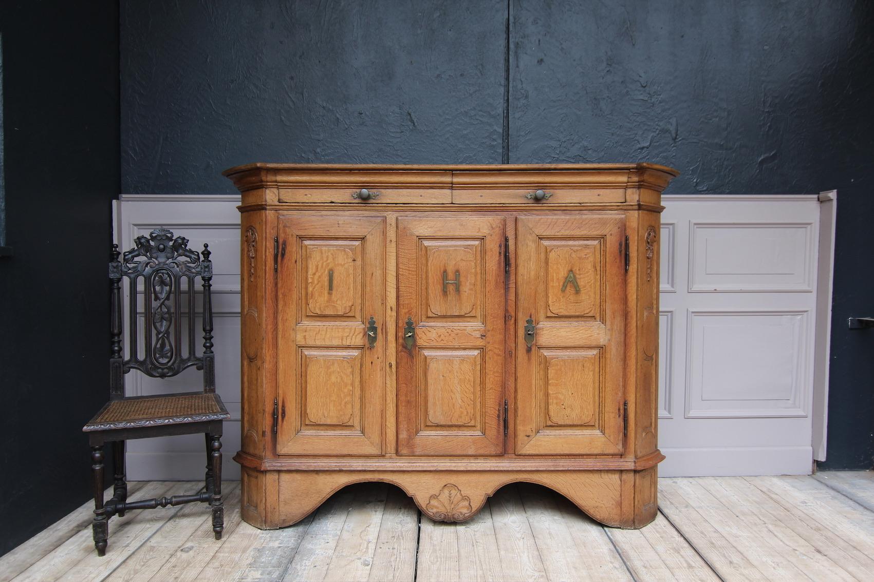A 18th century German Baroque sideboard made of solid oak. Probably from the Rhineland area.
Body with beveled, slightly rounded corners and matching cover plate. Double curved cut-out base with floral carving in the center.
3 doors on outside