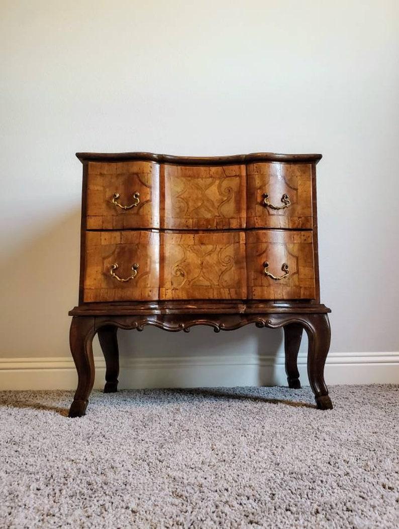 A unique signed original Baroque Sauteuse commode from the 18th century. Exceptionally executed, this elegant German mid-sized walnut cabinet presents with absolutely beautiful inlay works, including patchwork marquetry, scrolled inlay and fine