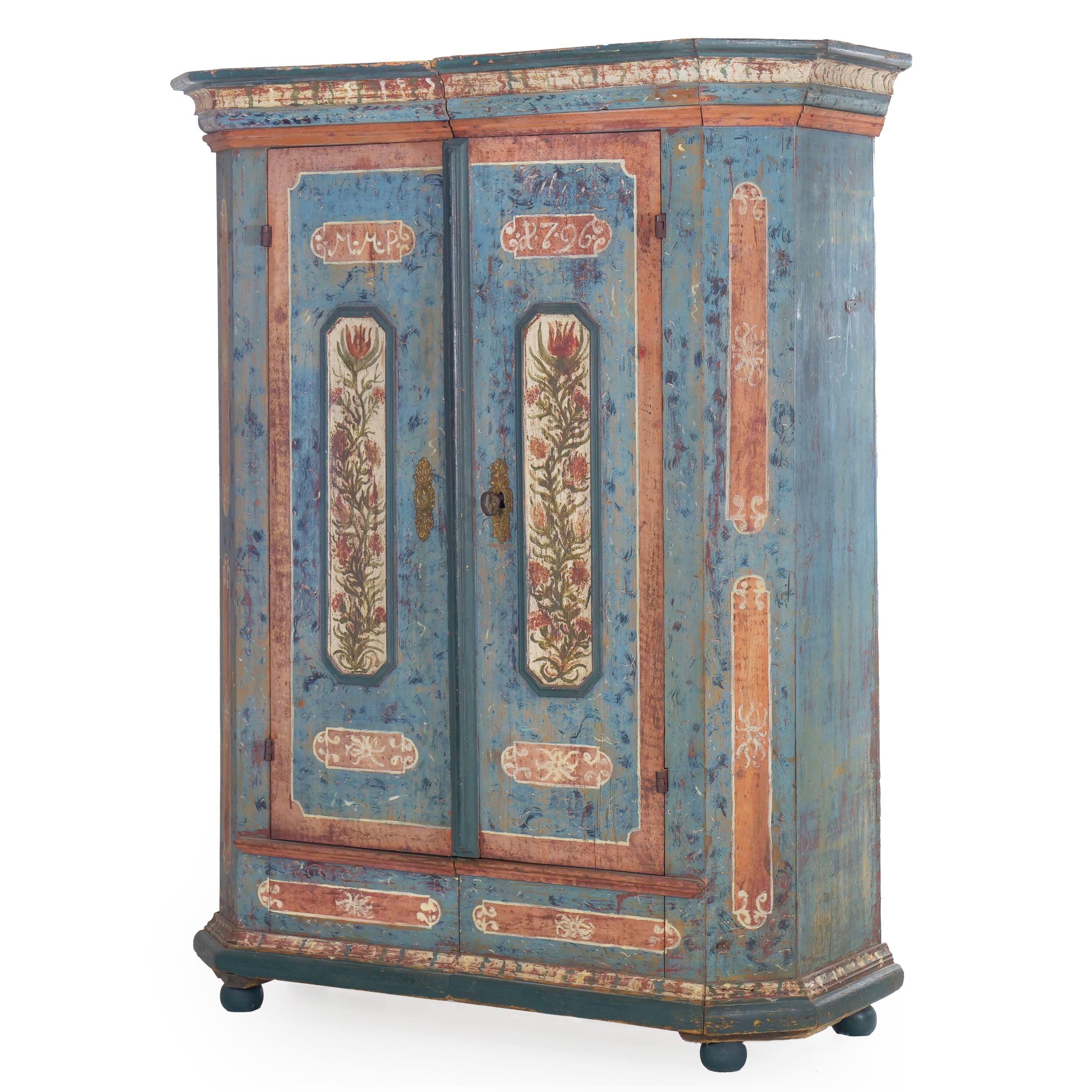 A gorgeous wedding schrank in early dusty robin's egg blue with coral painted highlights surrounding blue molded panels of cream with chaotic floral decorations in the doors, it has been conveniently built as a 
