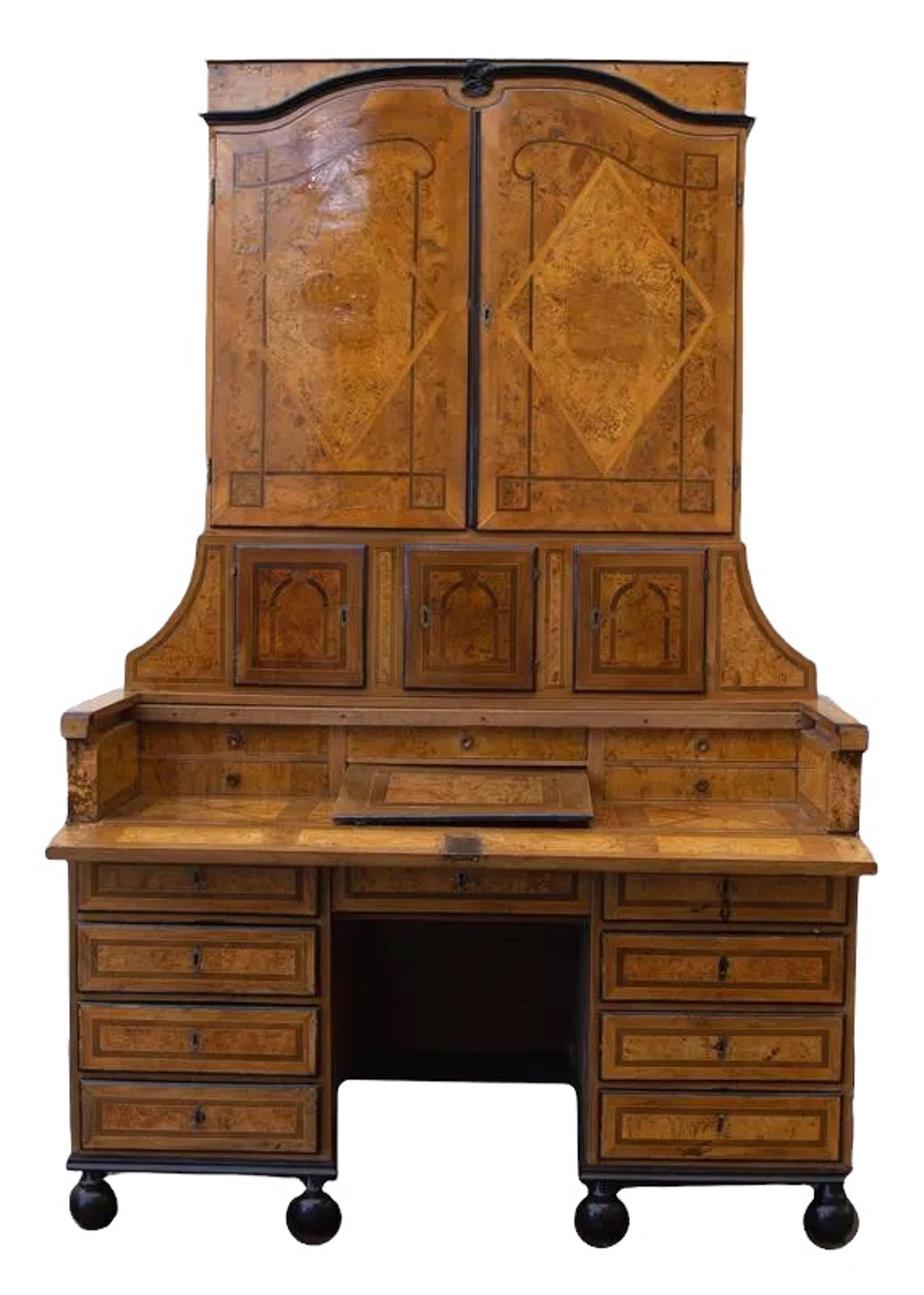 18th Century German burr elm and walnut secretary, adorned with ebonized trim and inlaid decorations and patterns. A pair of paneled doors over three small cupboards with beautiful details, over a pull-out writing surface with fitted interior, the