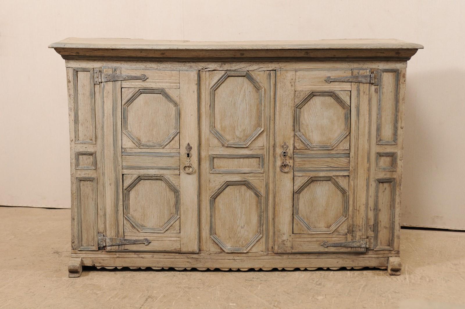 An 18th century German carved wood cabinet with geometric designs. This antique chest from Germany features a wood case with two doors heavily carved in geometric patterns, of octagonal and rectangular-shaped panels across the front side, a nicely