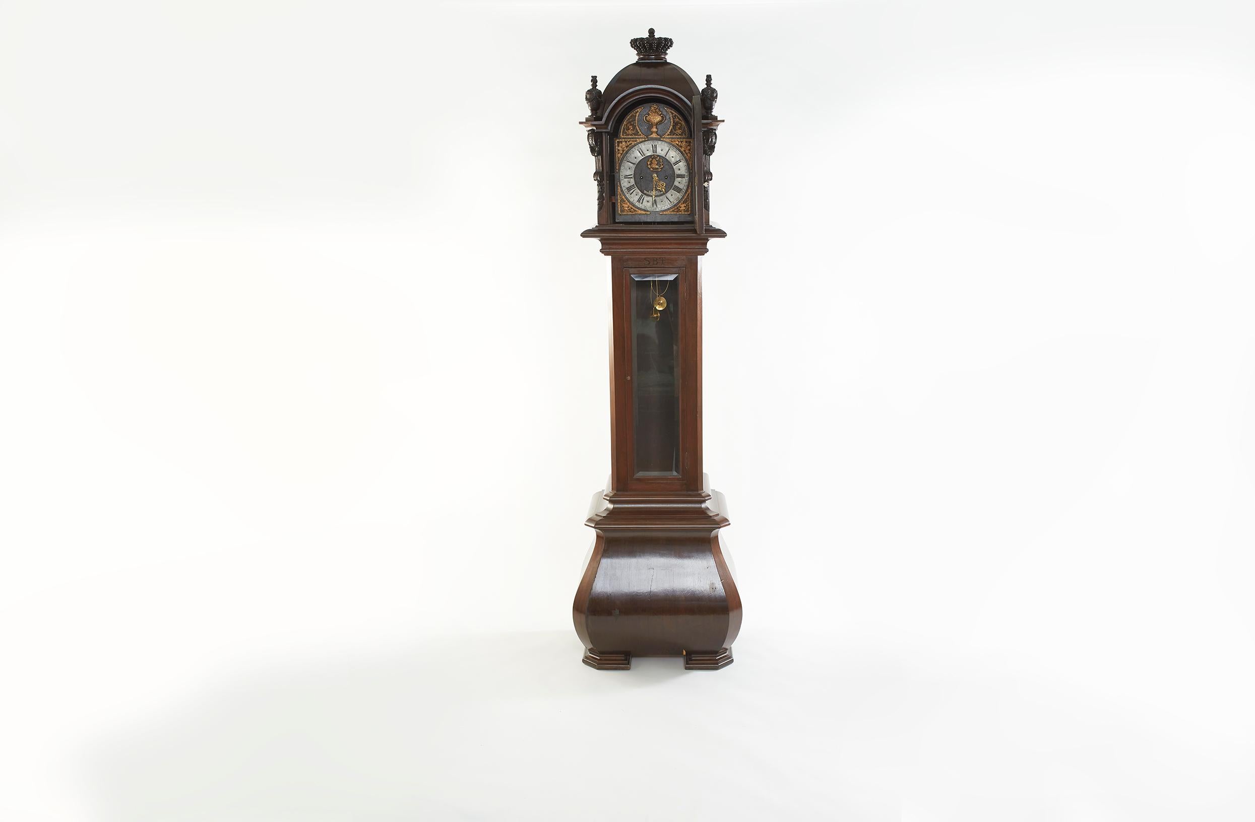 Mid 18th century walnut wood framed German 8-Day Grandfather clock. The tall case clock featured a dark walnut case with flared base, hood with half-columns and turned finials. Iron dial with silvered chapter ring and brass decorated spandrels. The