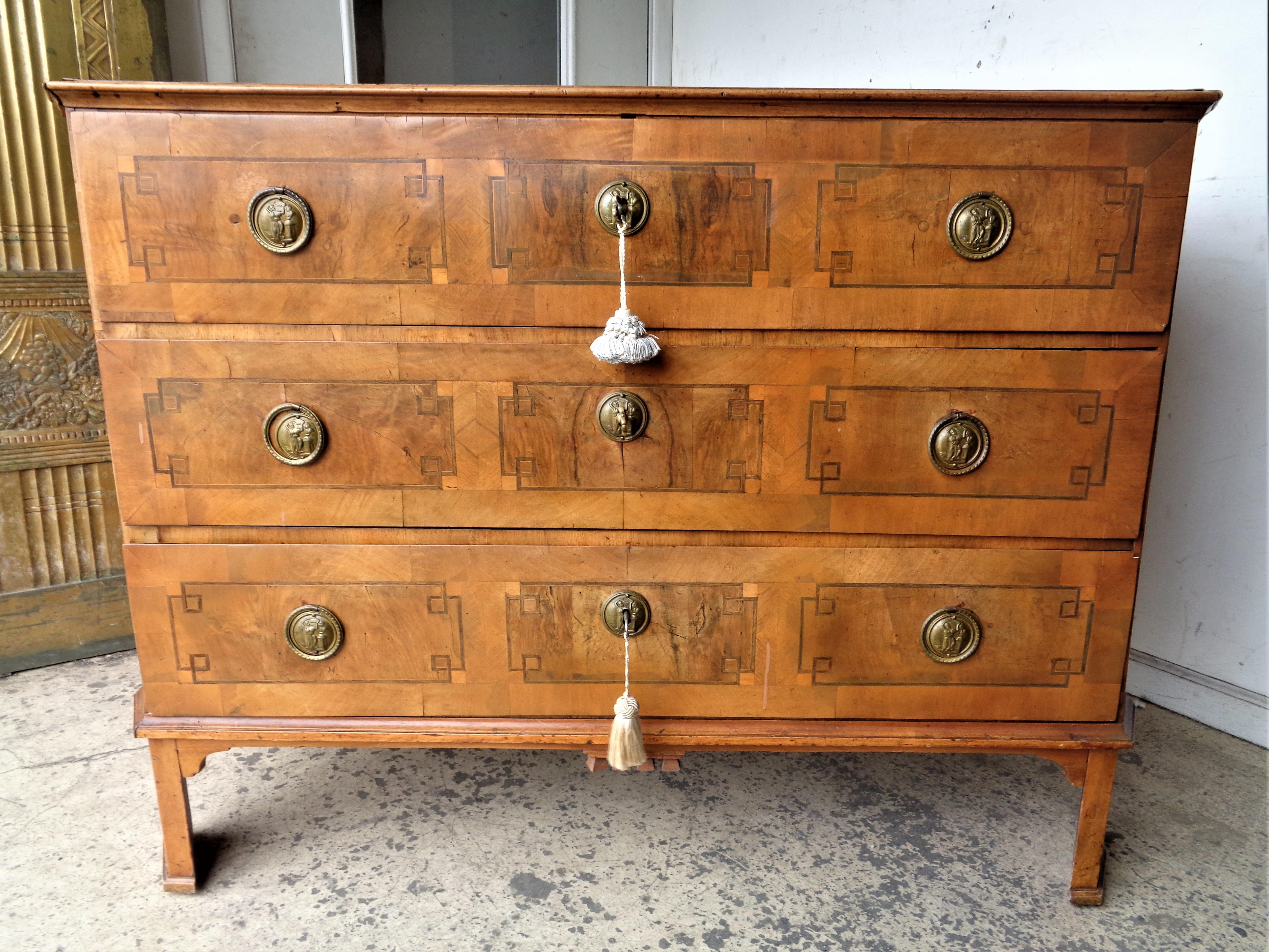 18th century neoclassical German fruit wood chest of drawers / large commode with early construction, all over inlaid design and extraordinarily fine and rare bronze hardware decorated with a classical figural scene in relief. Old refinish with