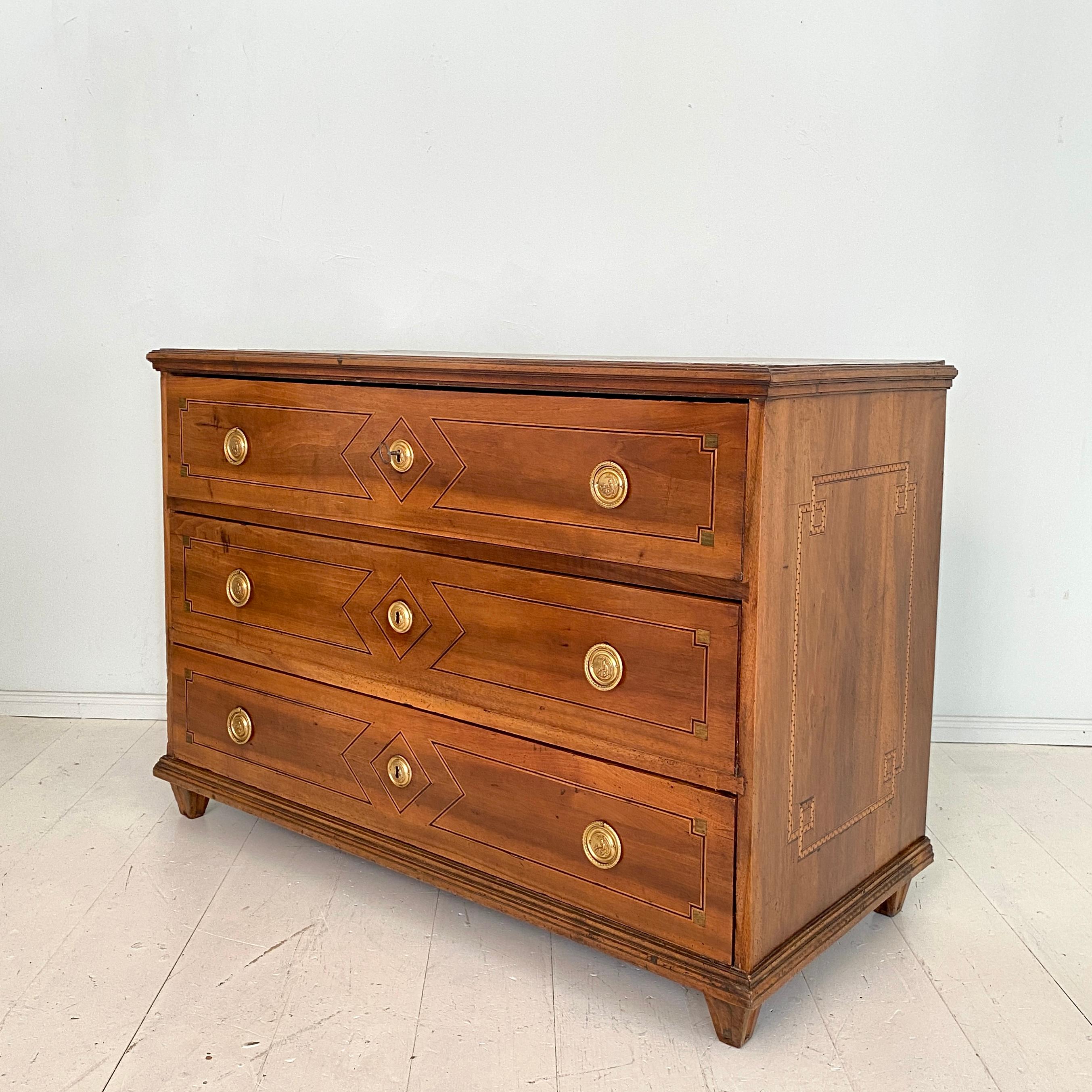 This 18th century German Louis XVI commode was build, circa 1780 in South Germany. The corpus of the chest is made out of solid walnut and the drawers out of pinewood. The Top and the Sides of the commode have got some great inlay banding . 
The