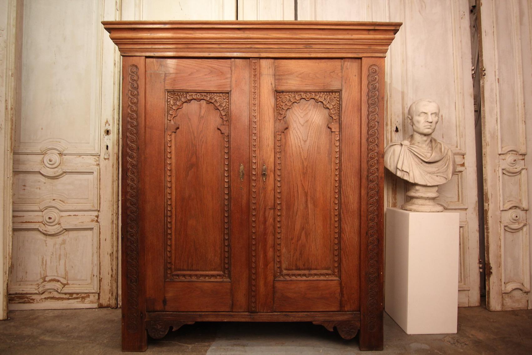 A 18th century German cupboard from the lower Rhine area.

Two-door oak corpus with projecting moulded cornice.
Doors and pilasters partially carved. Pilaster strips decorated with a wickerwork pattern.
Fixed shelves inside.

Dimensions: 
168