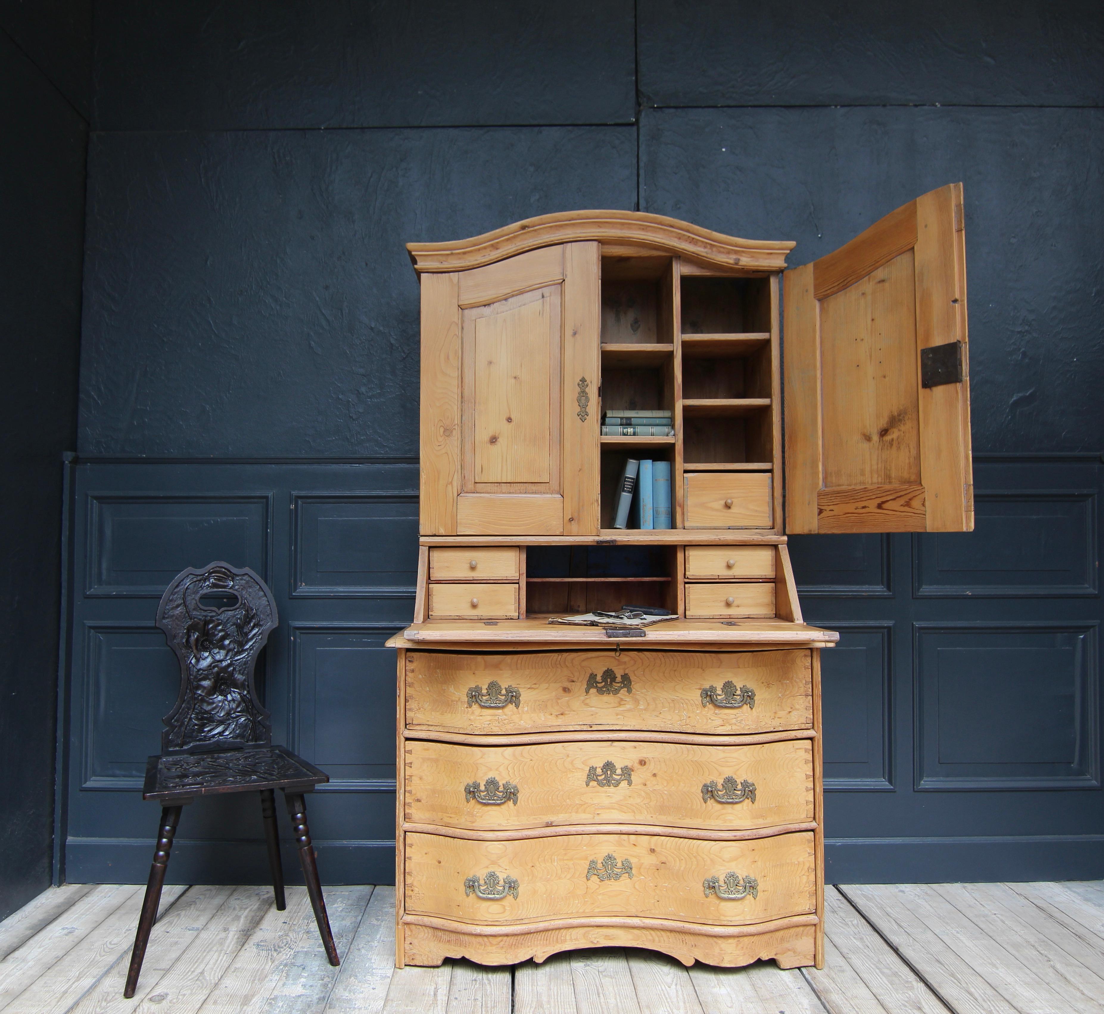 German provincial baroque secretary à deux corps from around 1750. Solid made in pine wood. 

Consisting of a three drawer commode lower part with S-shaped curved front and slightly protruding profiled top plate. On top of it the double-door upper