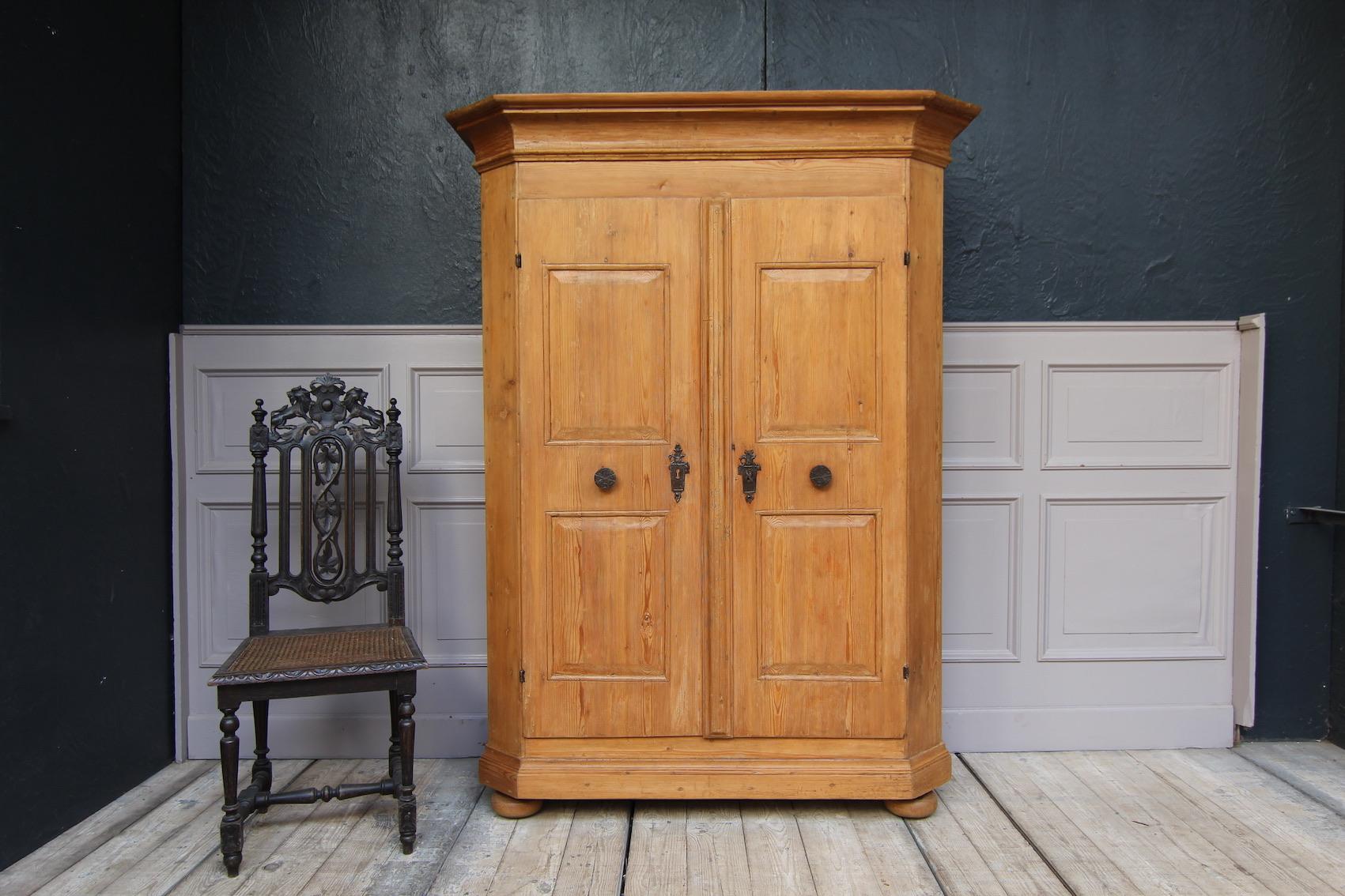 Southern German 18th-century baroque cabinet. Made of pine.
2-door body standing on 4 pressed ball feet with bevelled corners and protruding, profiled head strip. Doors on hand-forged iron hinges with the original hand-made lock (see photos). Solid