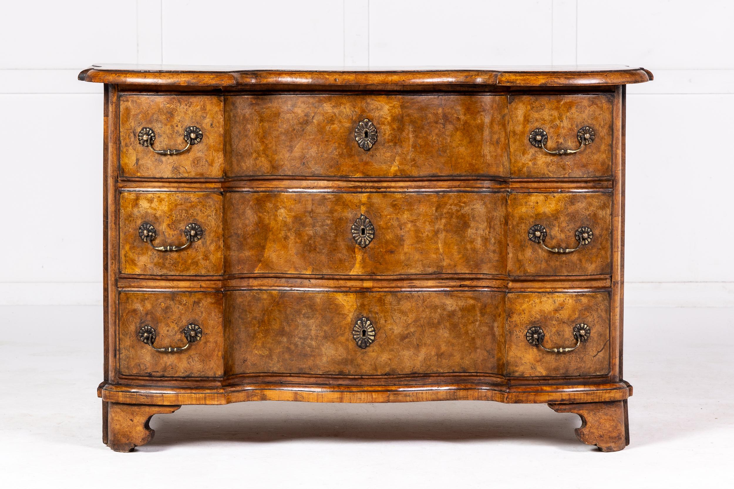 A Very Fine 18th Century German Commode of Drawers of Serpentine Form.

This piece in finely figured burr timber has an inverted serpentine form. The moulded top is of great colour and shape. Both the top and sides employ a very wide crossbanding.