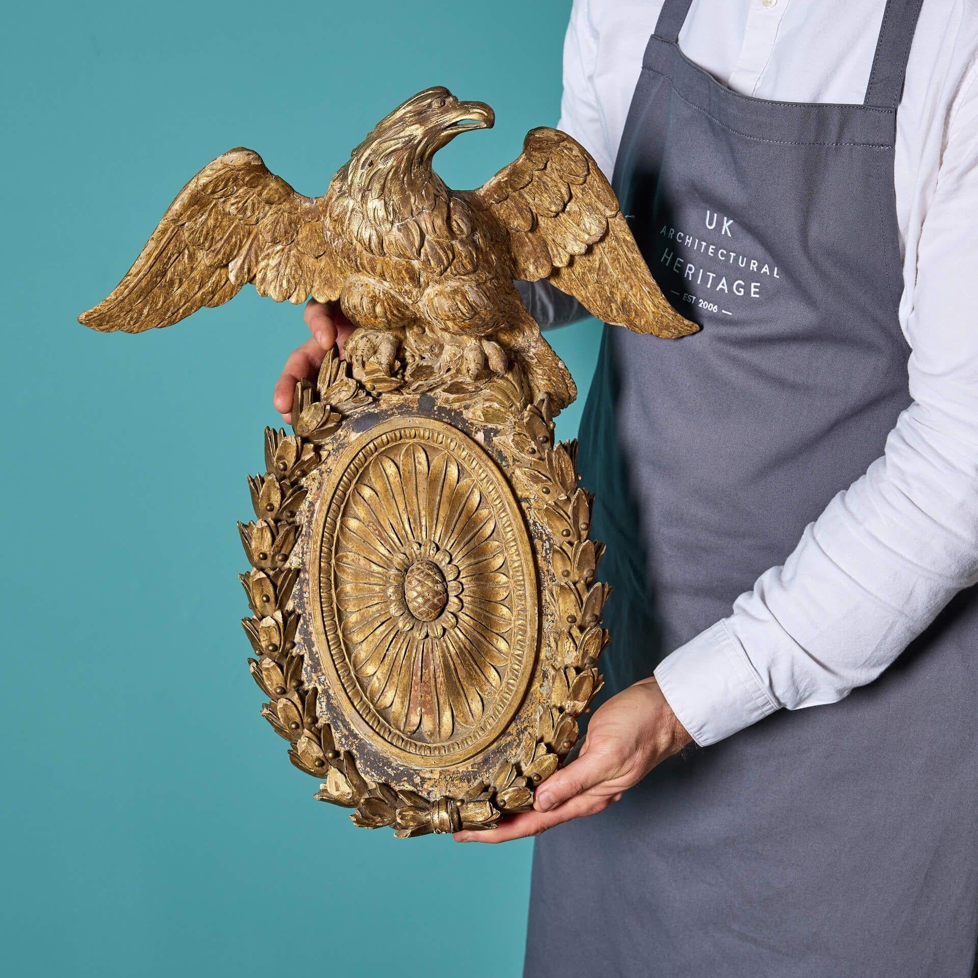 An original 18th century gilded and carved pine eagle above an oval patera, circa 1790.

Previously forming part of a Georgian mirror pediment (see pictures), this architectural eagle ornament is a testament to popular neoclassical styling of the