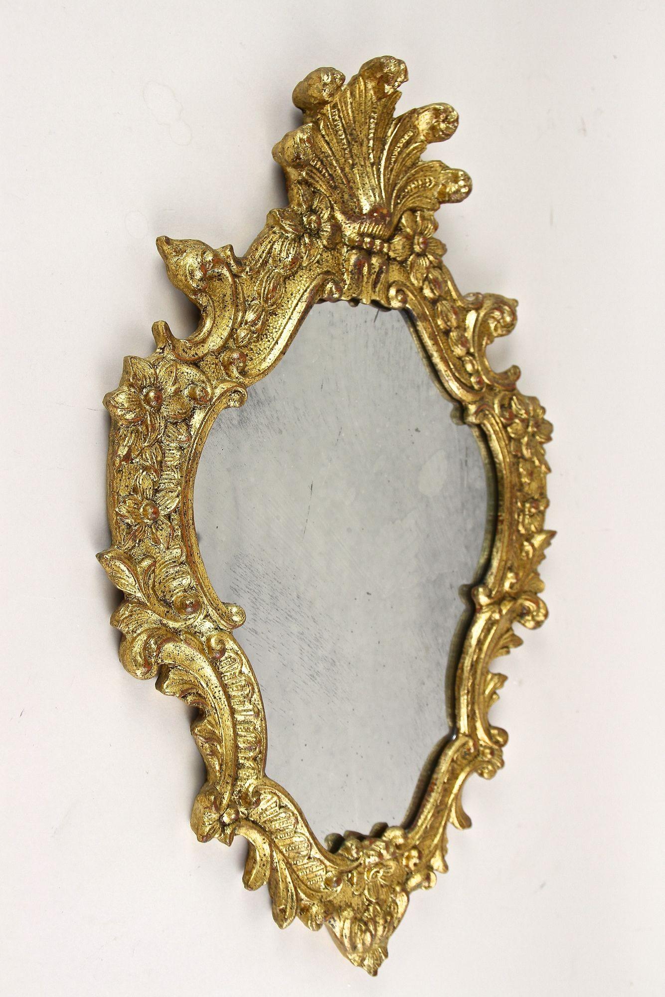 Extraordinary 18th century gilt wall mirror from the late baroque period around 1790 in Italy. The artfully handcarved frame shows different gilt techniques (gold leaf/ composition gold) and is adorned by elaborately handcarved unique floral
