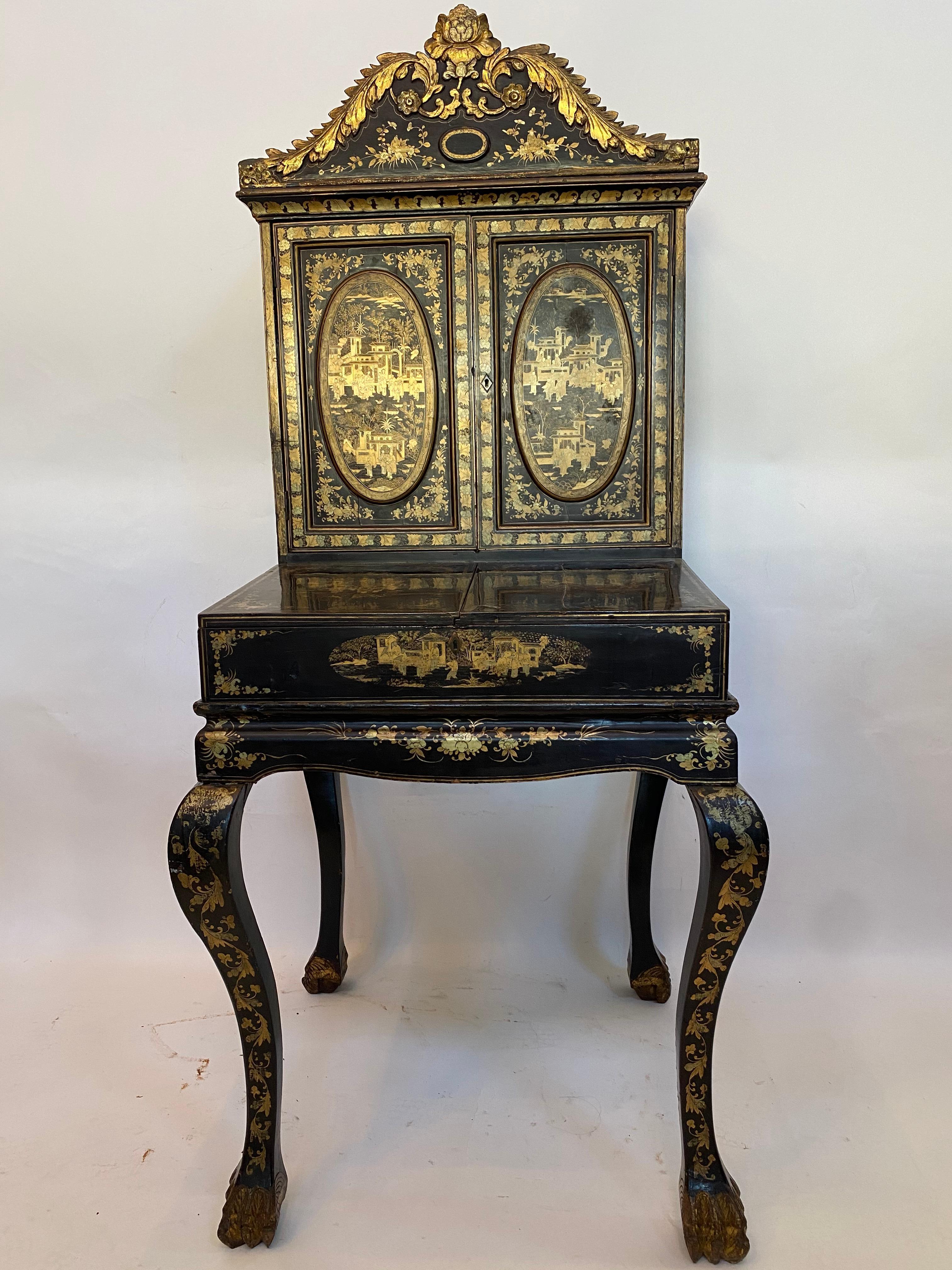 18th century gilt black lacquer Chinese cabinet desk, the rectangular-section body decorated with panels of landscapes, the superstructure of two panelled doors, enclosing an array of small drawers and a mirror panelled door. The projecting base