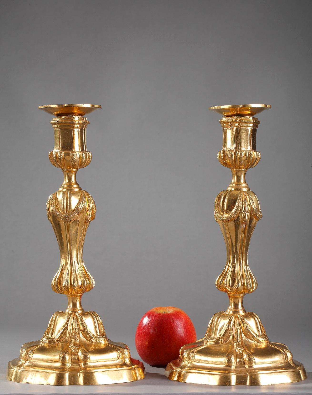French Louis XV-Louis XVI table candelabra centrepieces crafted of ormolu, or gilt bronze. The pair features a beautifully chiseled laurel garlands and acanthus leaf motif. The curved stems are supported by a high base also decorated with garlands.