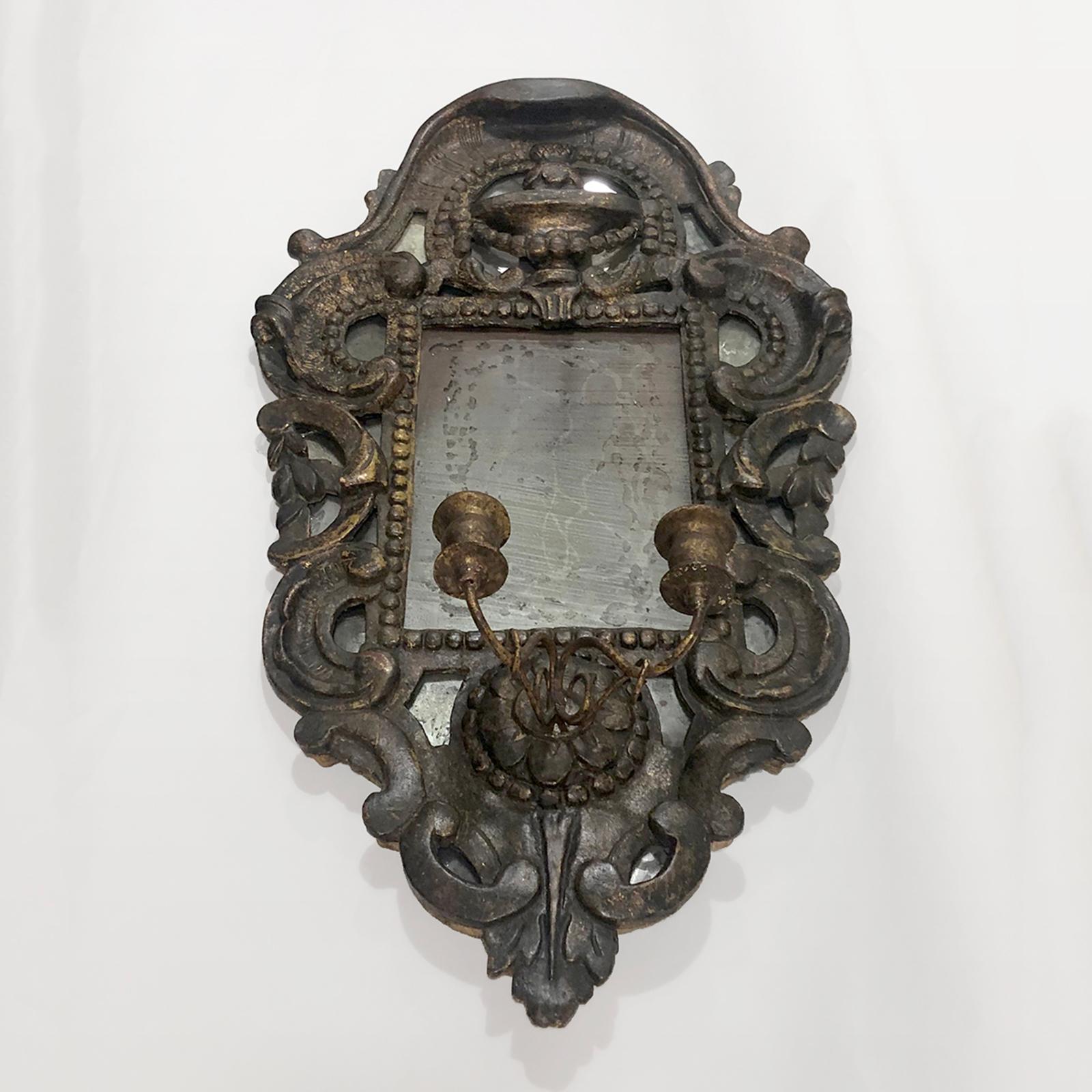 miroir en bois doré sculpté du XVIIIe siècle avec un gracieux motif de feuilles et de volutes. Au centre, en bas, un porte-bougies en métal doré. Avec le miroir vintage original.