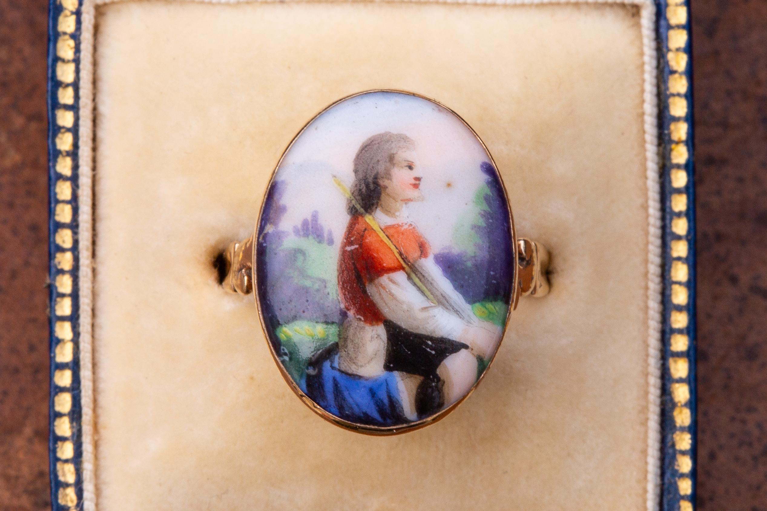 This rare antique late 18th century gold ring was made in France and features a painted enamel miniature of a shepherd boy holding a crook. This pastoral scene probably depicts David the Shepherd Boy, who gains fame and becomes a hero by killing