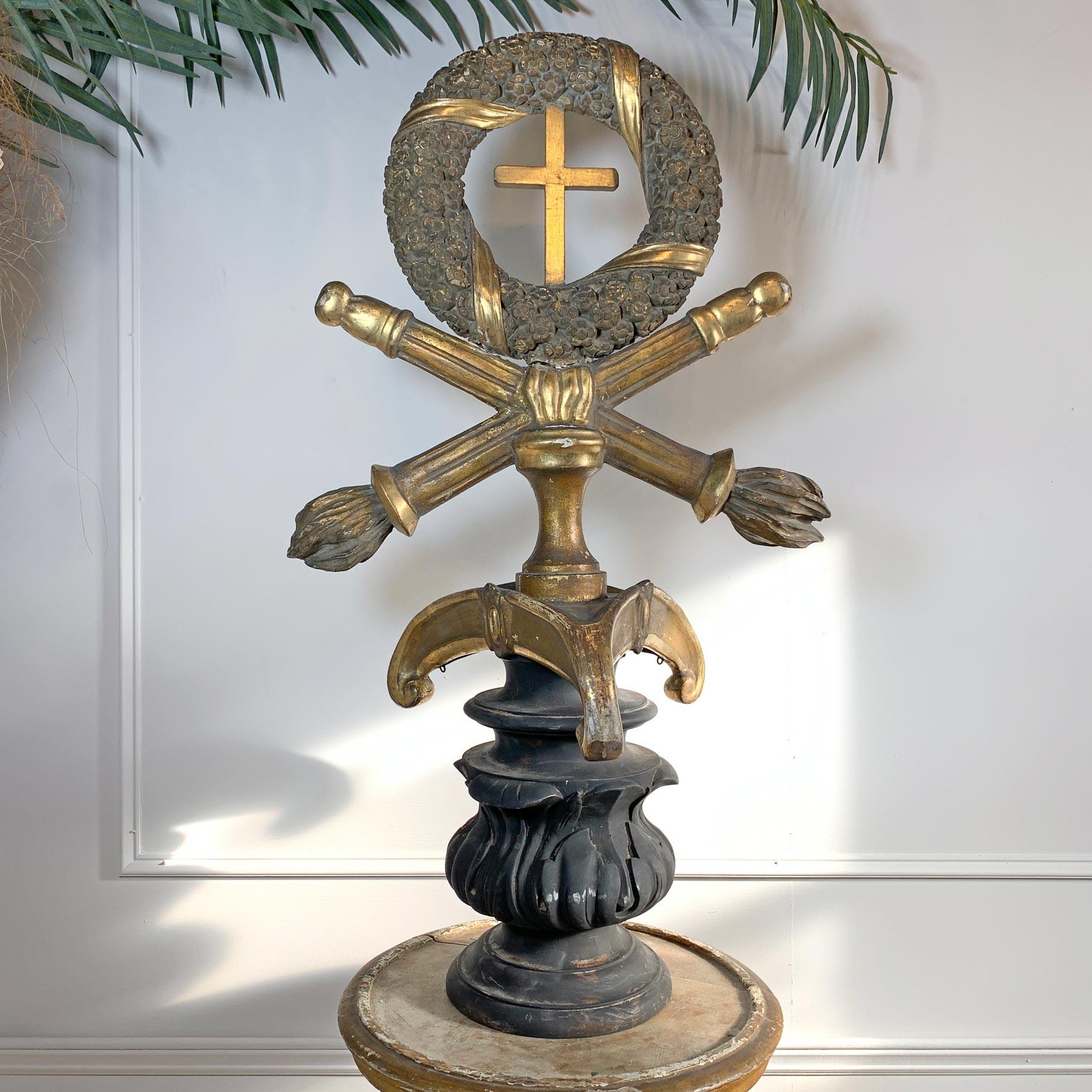 Wonderfully ornate gilt gesso over carved wood processional cross, probably northern Italy late 18th century. The large floral wreath with carved gilt ribbons, a small cross to the centre sits atop a pair of crossed Torchiere, all upon the spiked