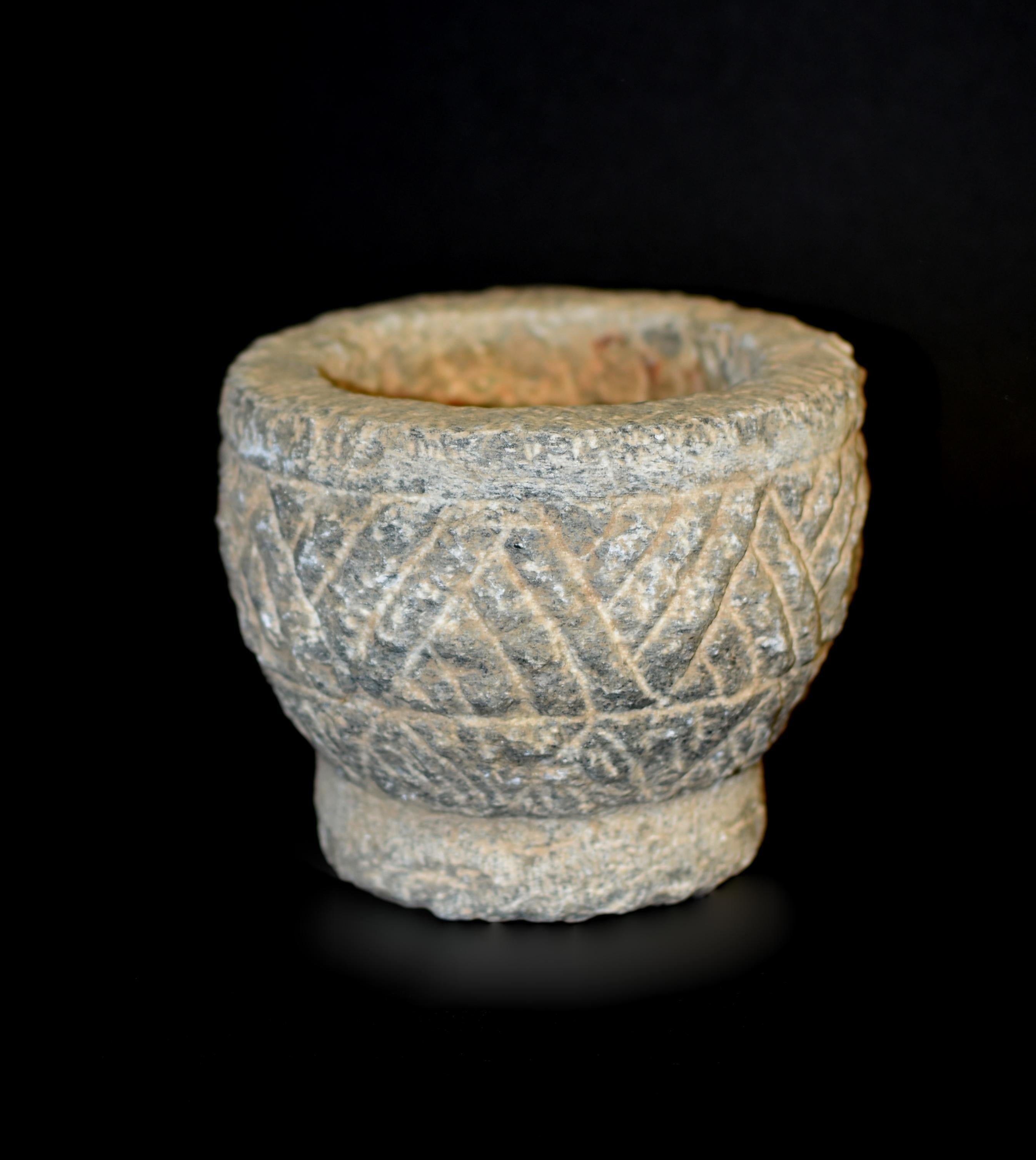 From Northern China a piece of great antiquity. The antique bowl of granite stone, hand cut and crafted, in conical form with a waisted base. Of white grey stone displaying natural patina and hand cut channeled grooves symbolizing prehistoric rice