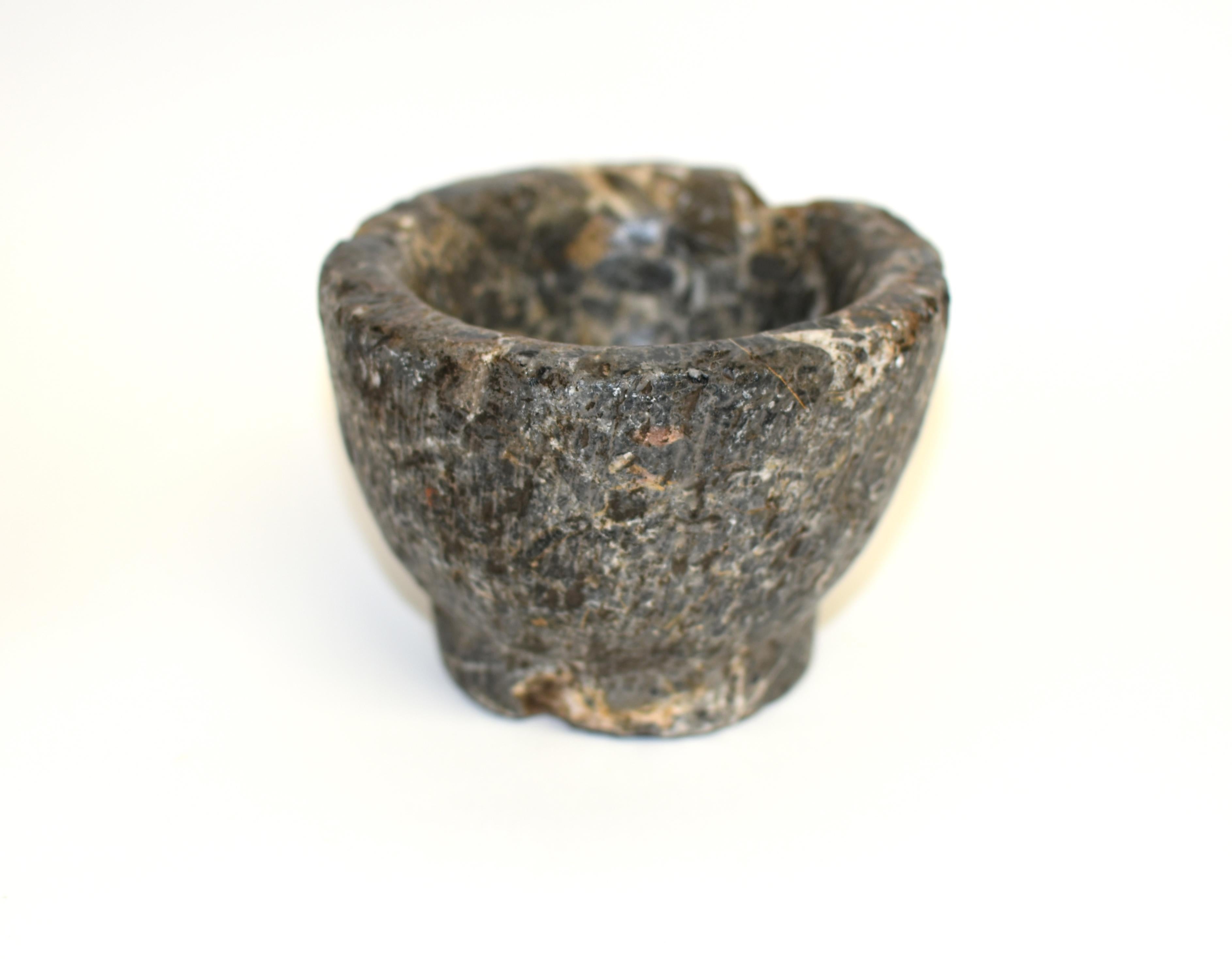 From Northern China comes a piece of great antiquity. The 18th century bowl of natural granite, hand cut and carved, in conical form with a round base. Of grey stone displaying natural stripes and aged patina. Exteriors hand scored with vertical
