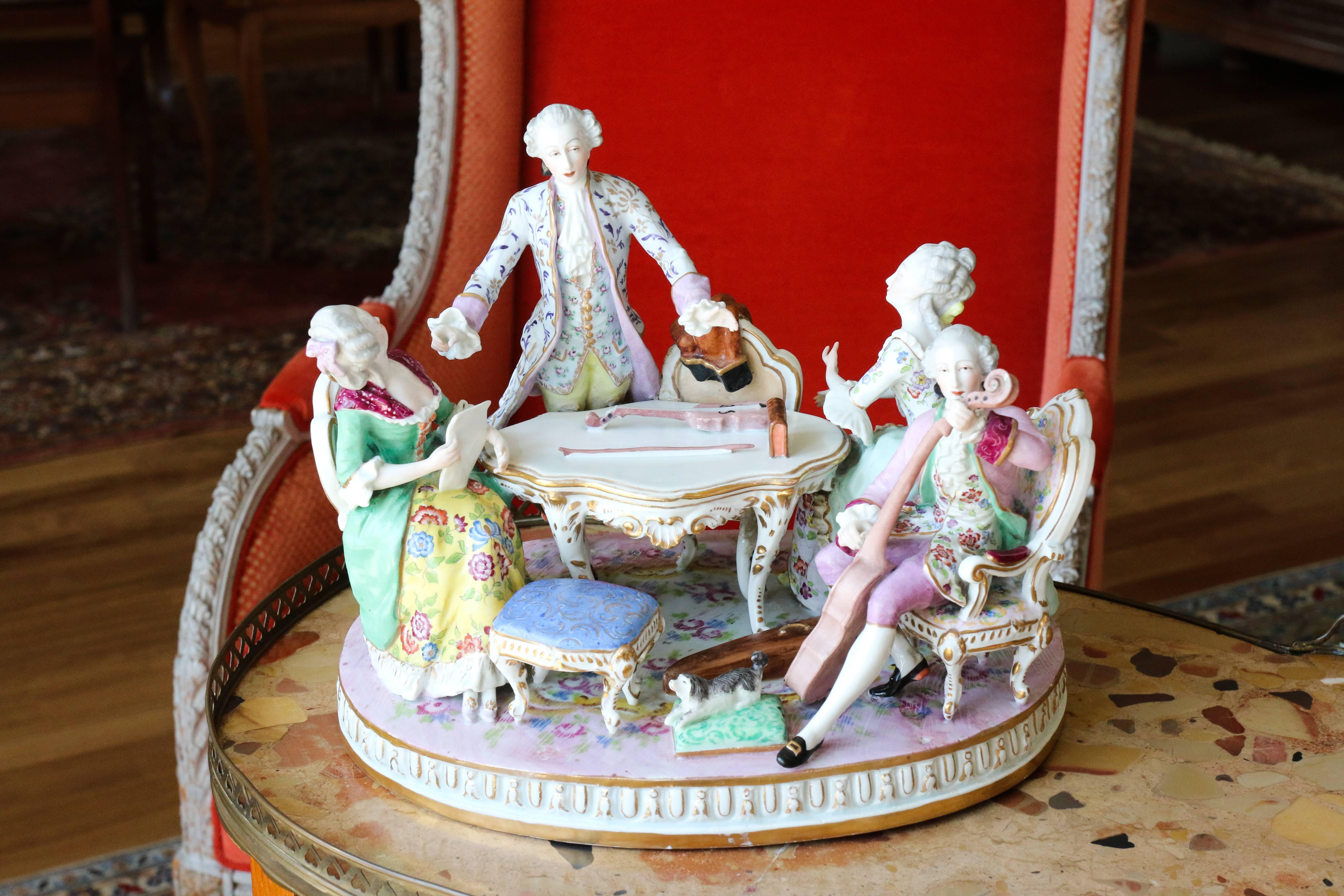 Group in polychrome Saxe porcelain called 'The singing lesson'.
A maestro beating the rhythm for two courtesan’s vocalists and
a musician granting his viol in a decoration of fine furniture in vivid colors.
Very good condition. The mark could be