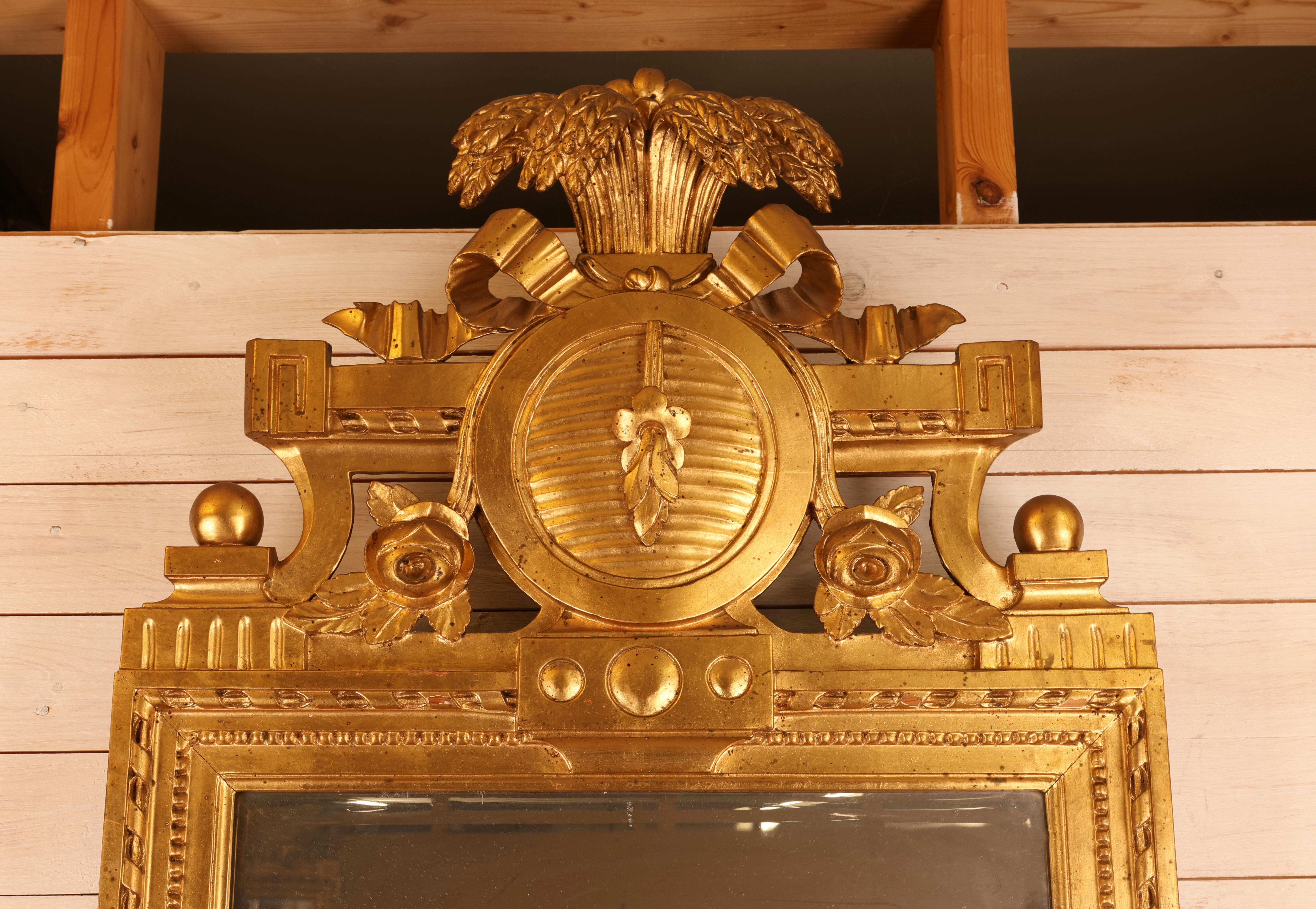A Gustavian mirror made in Stockholm in the 18th century, bearing the signatures of Johan Åkerblad and the gilder Erik Törngren. The mirror is crafted from gilded pine and has mercury glass. It is decorated with carved wheat sheaves, roses, a ribbon