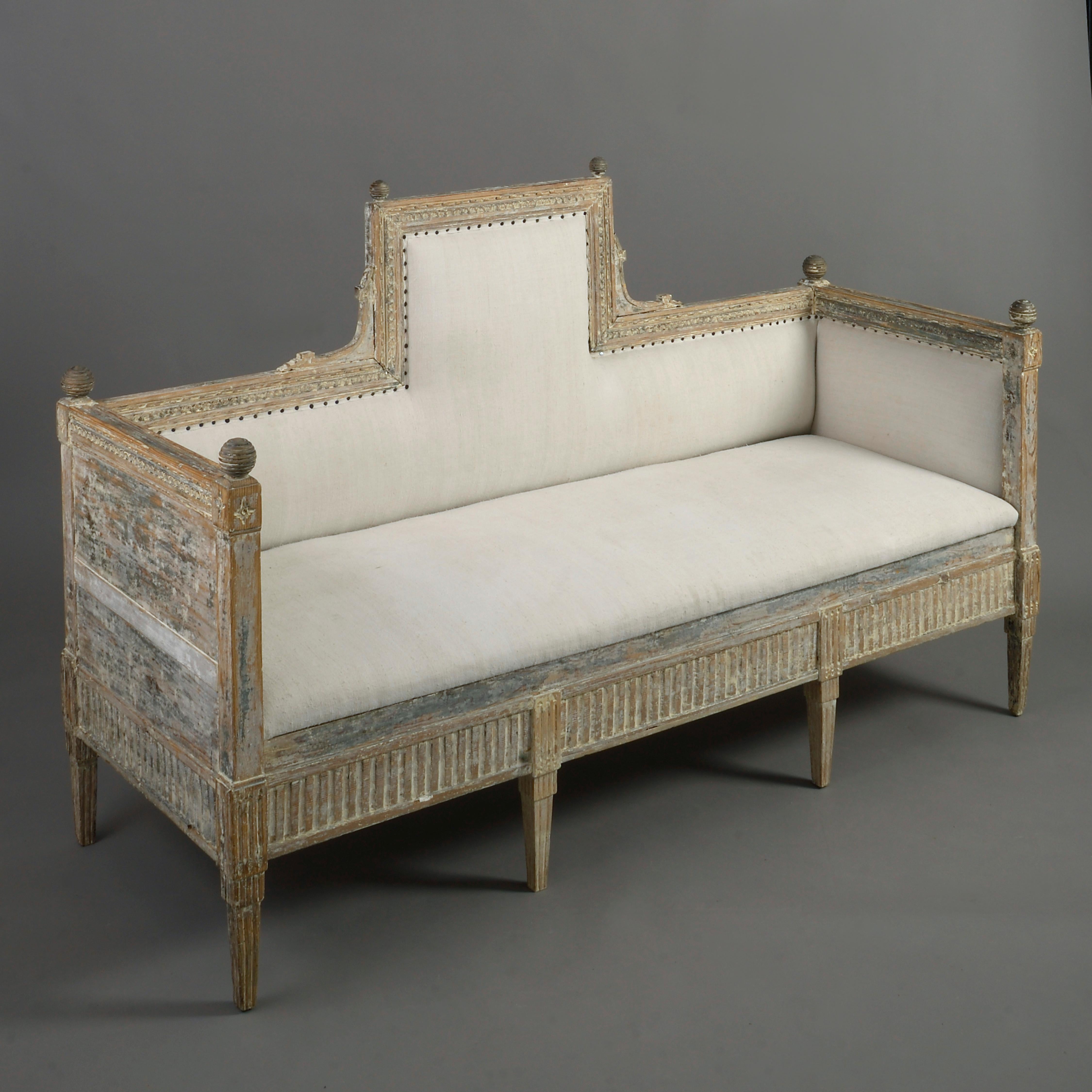 A very fine and rare late 18th century carved, painted upholstered sofa, the back with raised central section and carved with a palmette motif, the corners all surmounted with ring turned spheres, all above a fluted frieze and supported upon square