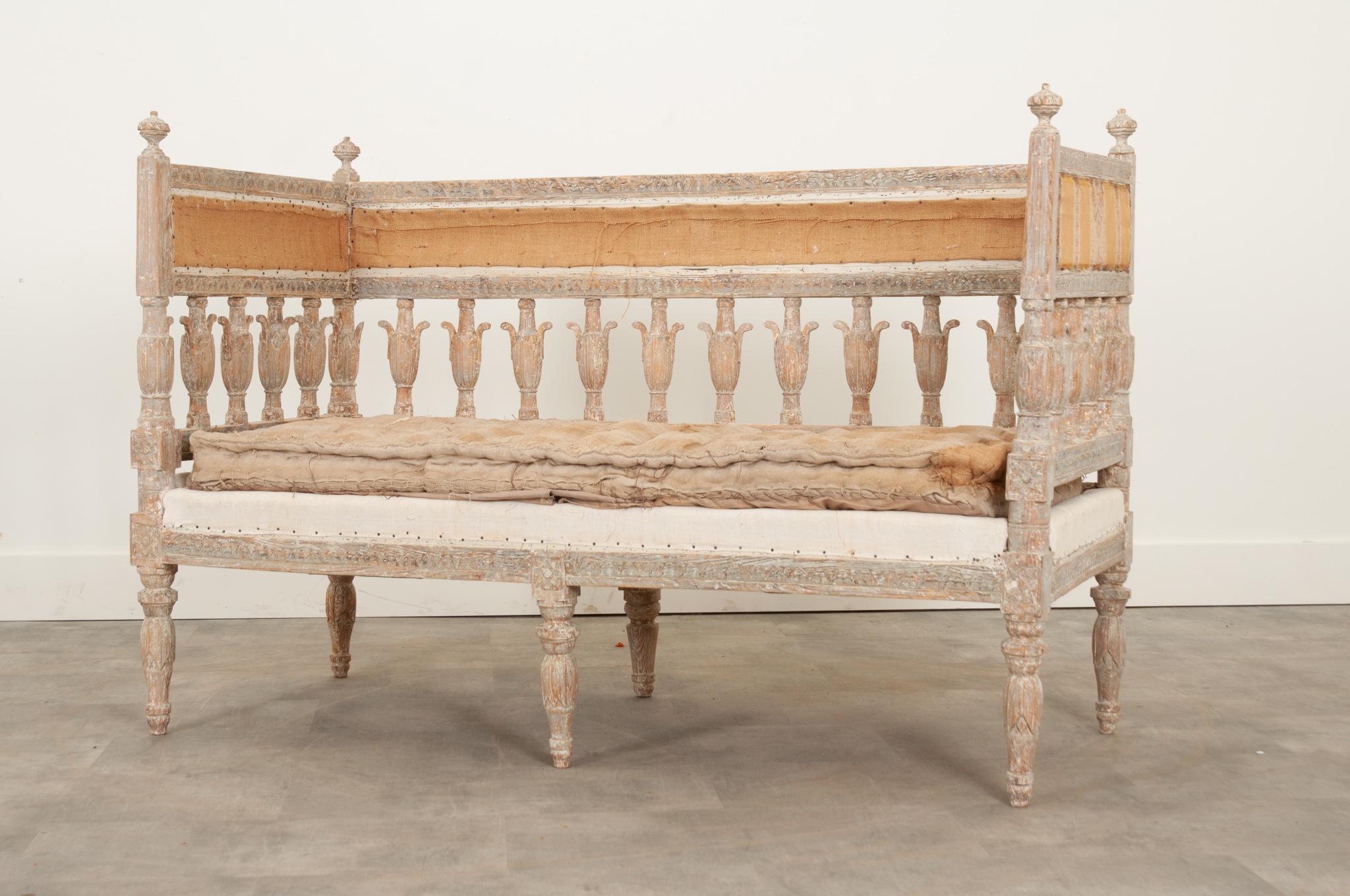 This eye-catching 18th century Swedish painted settee is a jewel of a find. The hand carved details throughout are beautifully accentuated by the original pale gray painted finish. A high gallery rail on three sides- perfect for bunching up pillows-