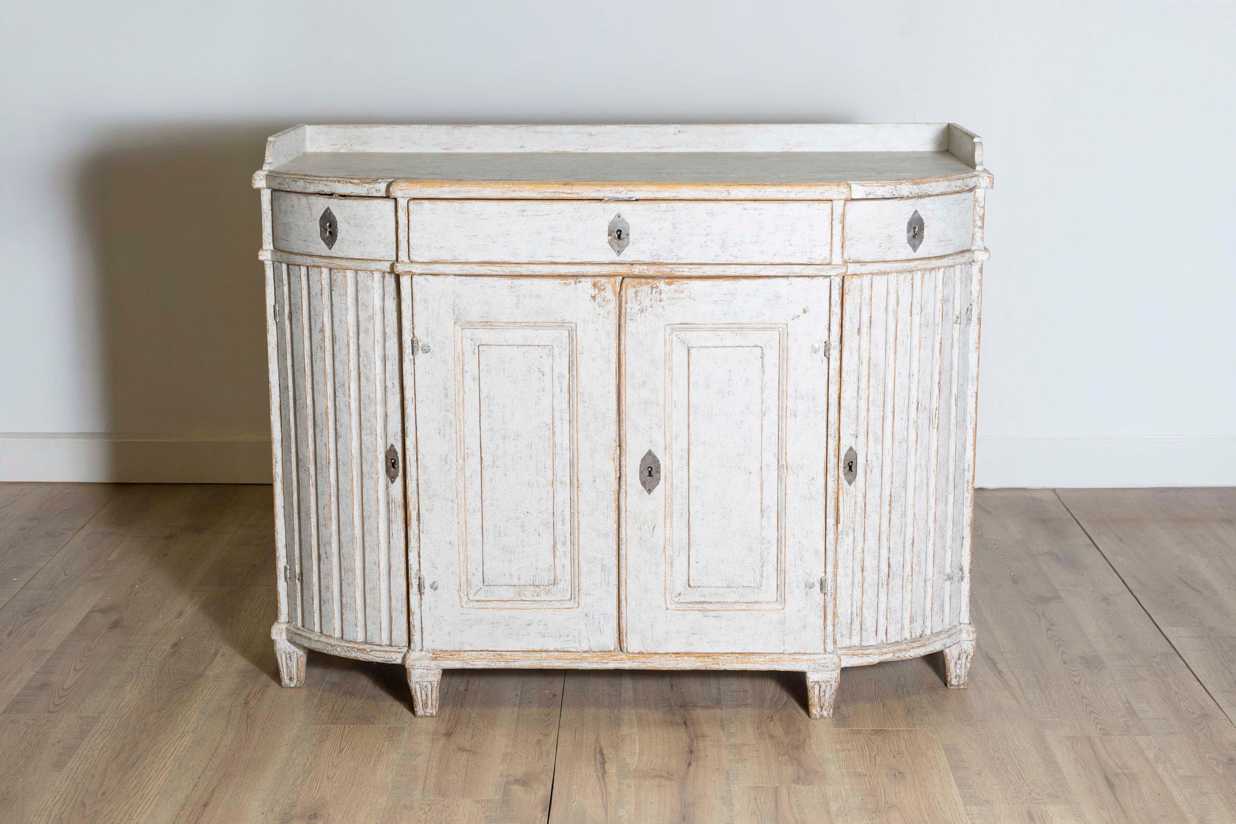 This 18th-century Gustavian sideboard, circa 1790, is a remarkable example of Swedish neoclassical design, blending functionality with timeless elegance. Constructed from pine, the sideboard features a painted finish in a soft, distressed white