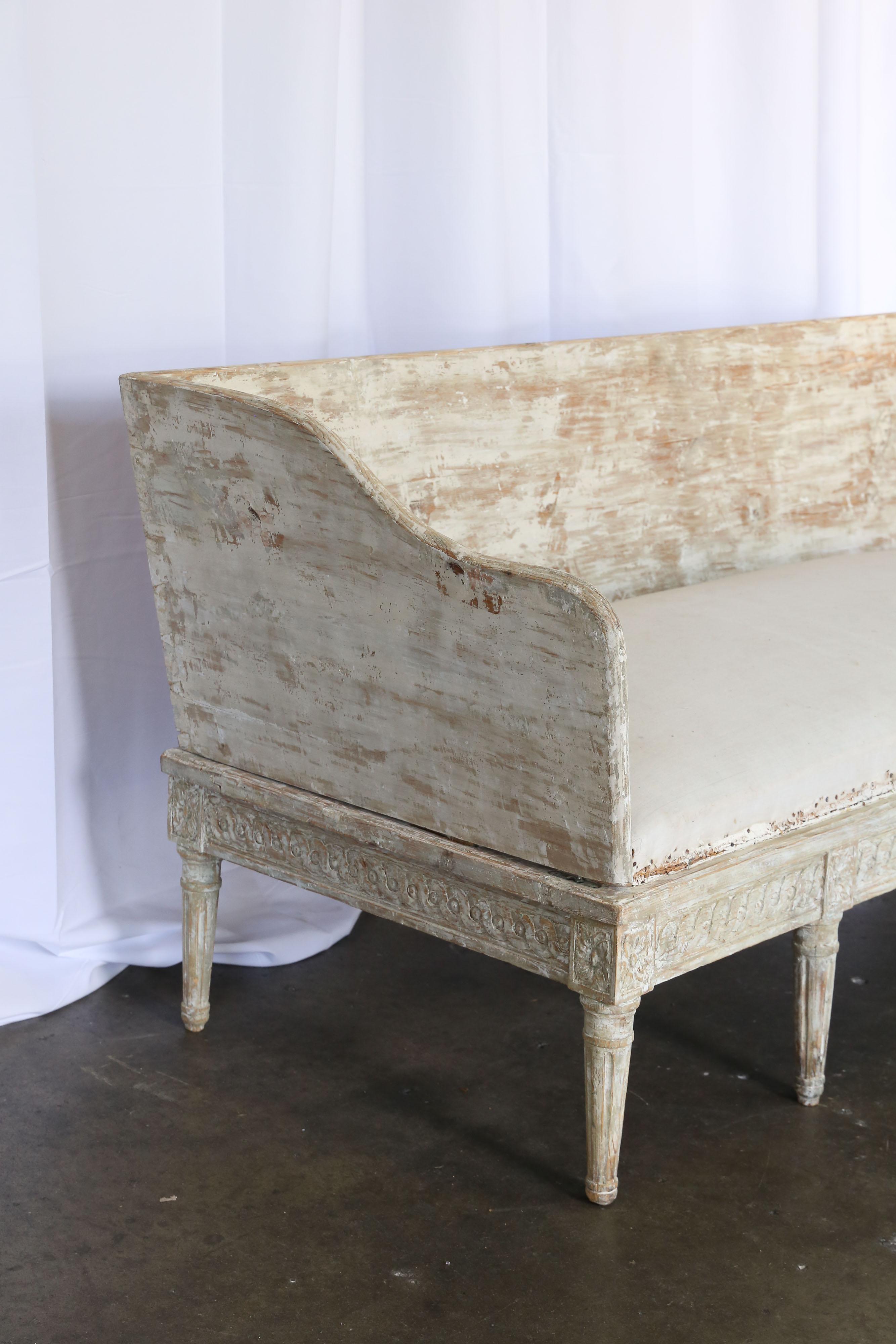 18th century Gustavian sofa with original paint dry scraped as in the European fashion. Round tapered legs and detailed carving around the sides and front of the sofa. At the top of each leg is a rectangular carved block medallion.
