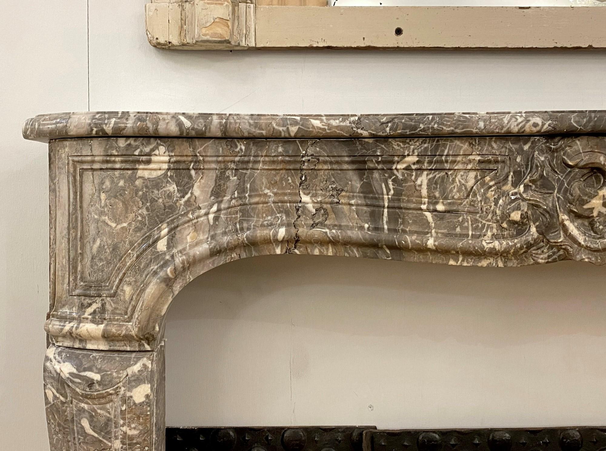 Hand carved gray French marble mantel in the Louis XV style with white veining from the 18th century. This can be seen at our 333 West 52nd St location in the Theater District West of Manhattan.