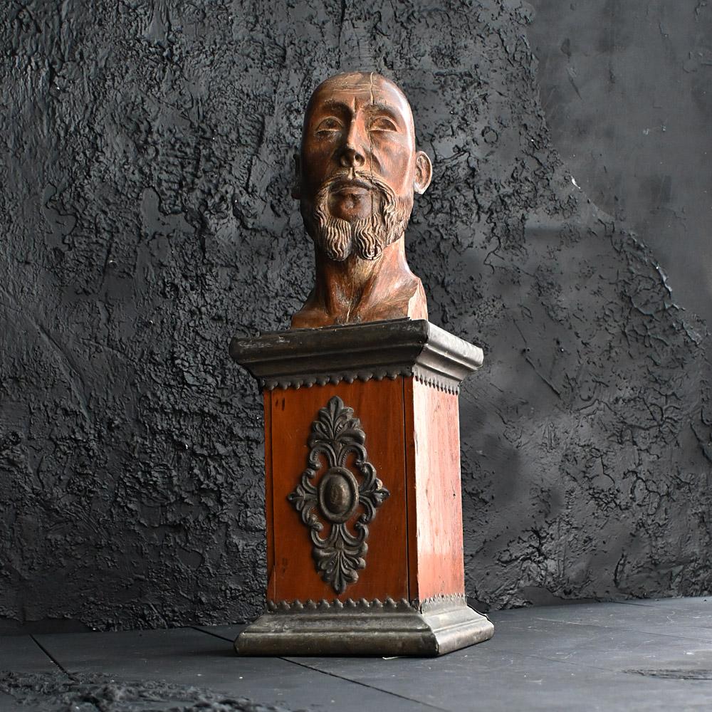 18th Century Santos 
A finely carved late 18th Century wooden Santos or Apostles head. Bears traces of original paint to top of its head. Mounted on its original period heavily patinated brass repousse ornamented wooden base.

Size in inches: H 22”