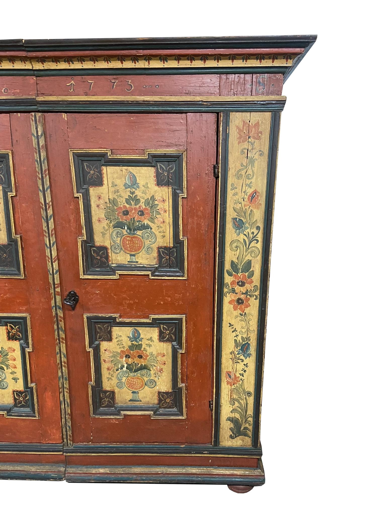 18th Century painted Bavarian pine cupboard hand painted in red, tan, and blue black. Four framed yellow squares depicting bouquets of flowers and two panels on the edges depicting more flowers.

Dimensions:
78.5?H x 79.5?W x 23?D.