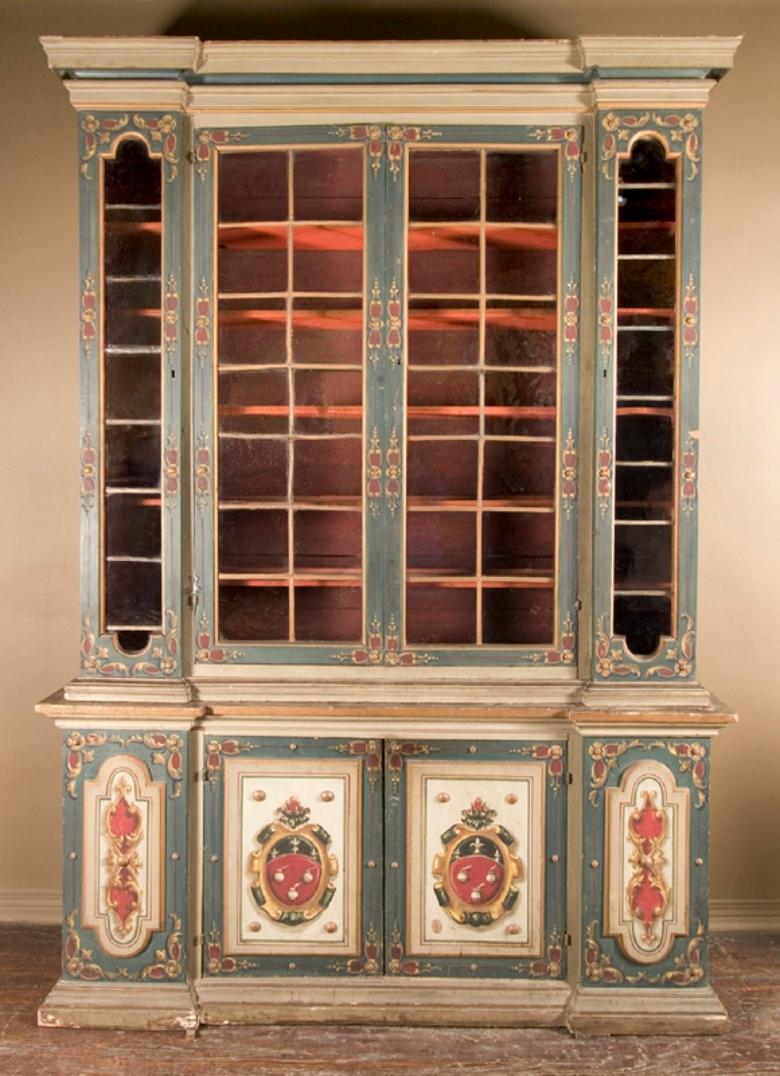 Este magnífico armario italiano del siglo XVIII está bellamente pintado y llega a la tienda procedente de Bolonia. En la parte inferior, la pieza tiene 4 puertas cubiertas con un detallado diseño heráldico. La parte superior presenta 4 puertas,