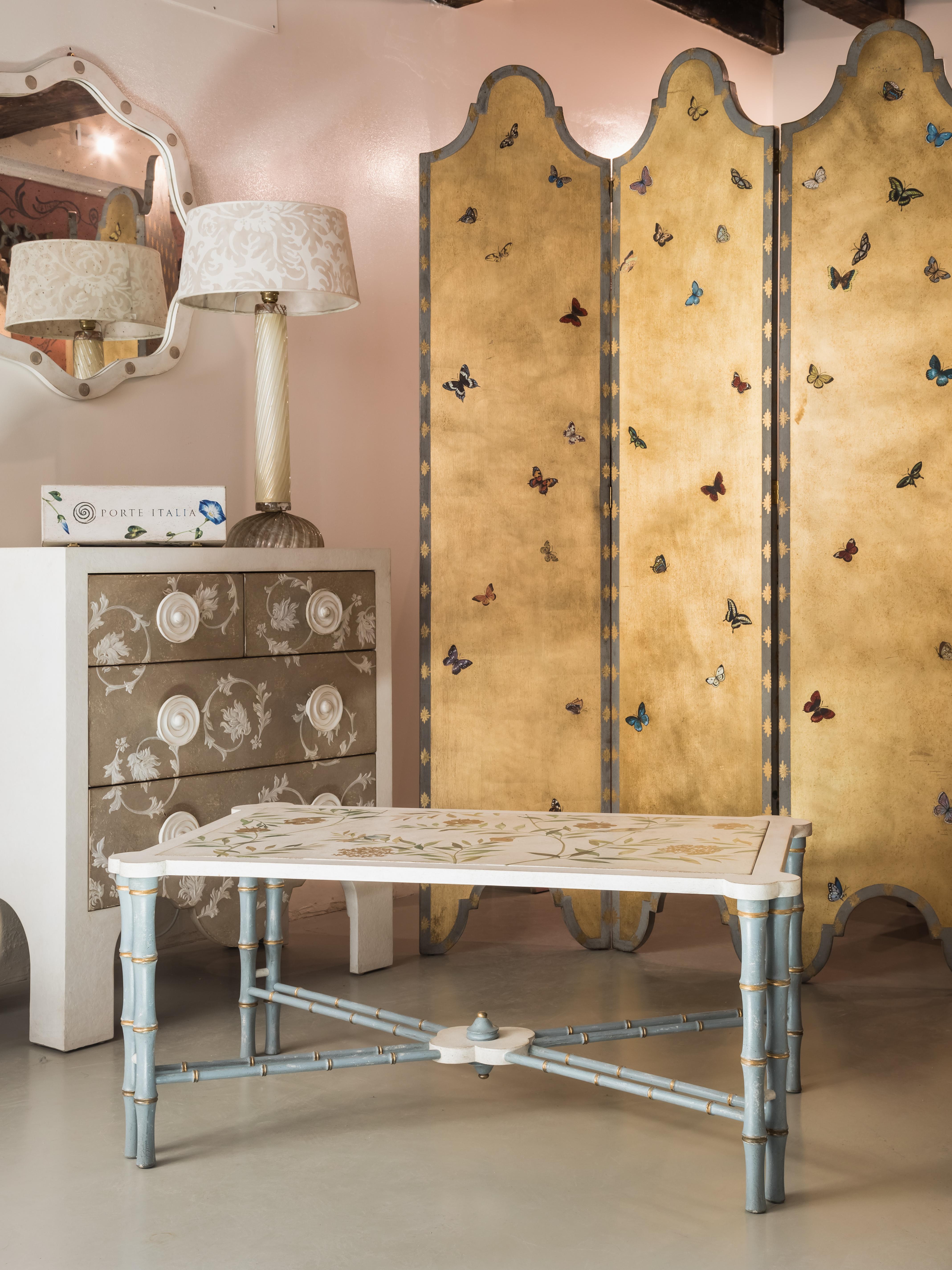 De notre collection de meubles peints à la main, nous avons le plaisir de vous présenter notre table basse Marco Polo en bambou bleu-gris avec décor de feuillage chinoiseries. 
Nous avons ajouté des accents dorés pour mettre en valeur la silhouette