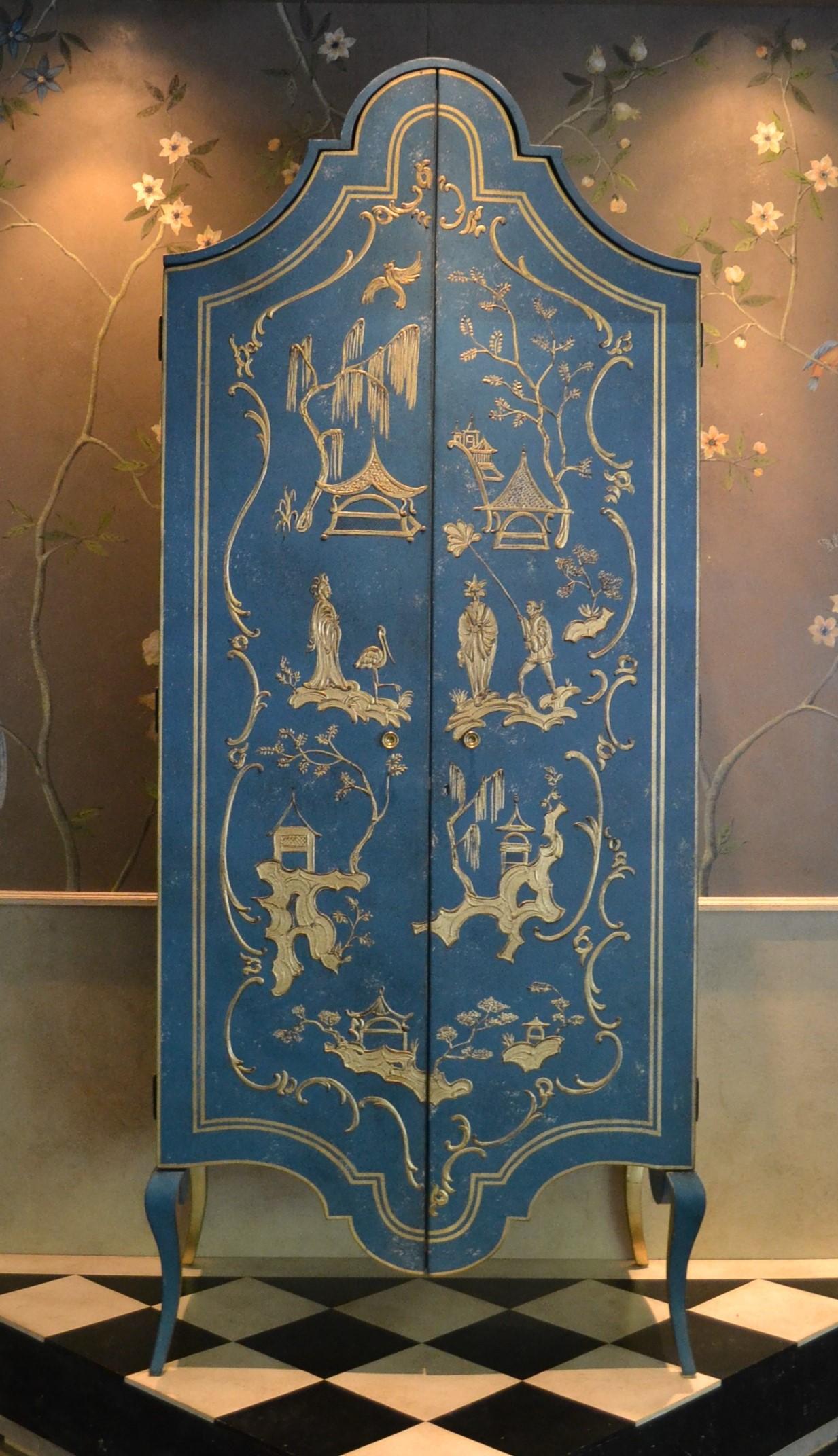 Dans notre collection de meubles peints à la main, nous avons le plaisir de vous présenter l'armoire Tevere, d'un bleu de mer profond, avec un décor en relief de chinoiserie dorée. 
L'ensemble de la façade de cette armoire spectaculaire devient une