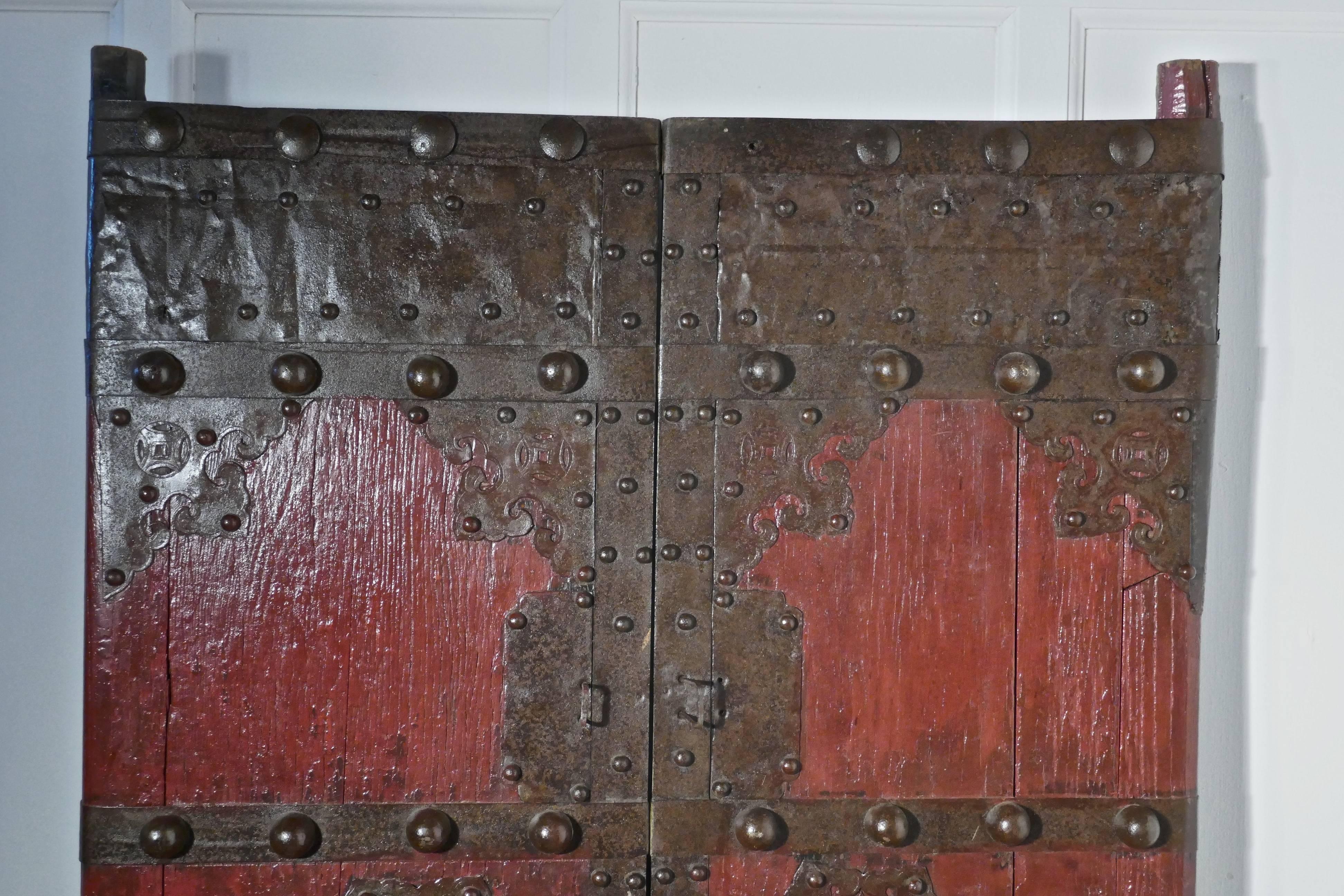 18th century heavy painted oak and iron oriental doors

This pair of doors dates back to the 18th century, they are made in Oak which is over 2” thick
They have old red (for luck) paintwork, decorative iron work and a large ring handles on the