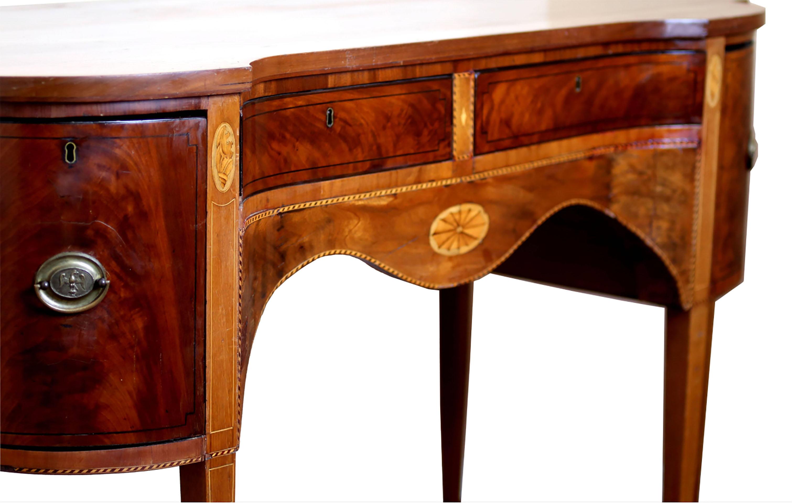 Striking sideboard buffet with concave center in mahogany, satinwood, holly, and ebony. Center section contains silver and linen drawers while outer deep drawers housed liquor and wine cooler. Banded inlay throughout with conch and central spider