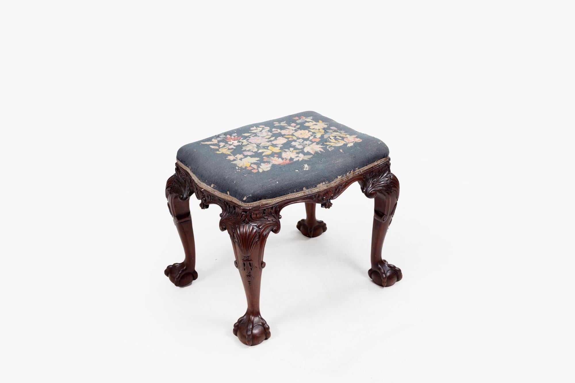 18th Century highly carved Irish cabriole leg stool with scrolling acanthus leaf and shell detail to the knees and terminating on four ball and claw feet. The top is upholstered with petit point embroidery needlework.