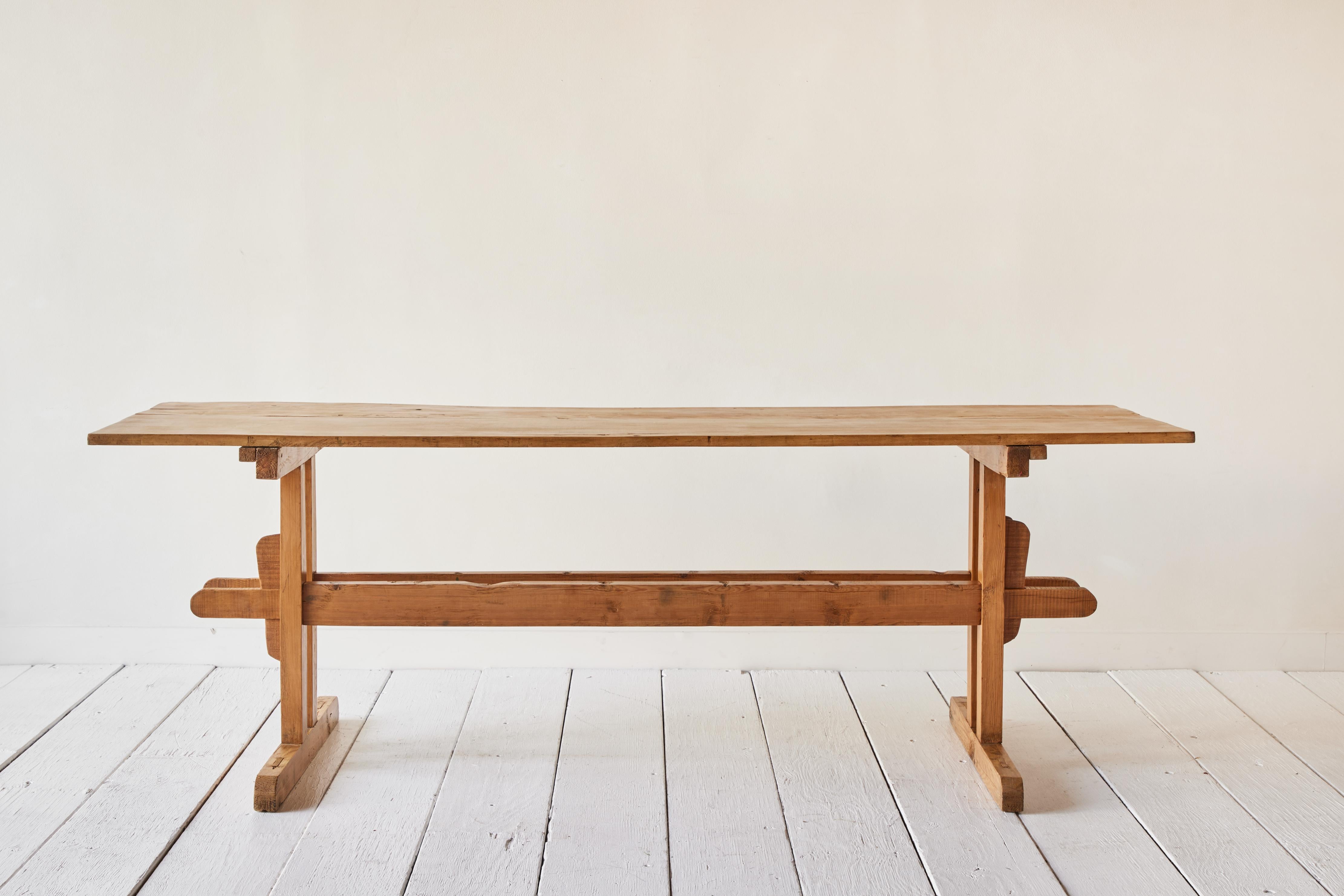 Antique 18th Century trestle farm table from Hungary. A centralized base allows ample seating around a table. Made of solid pine.