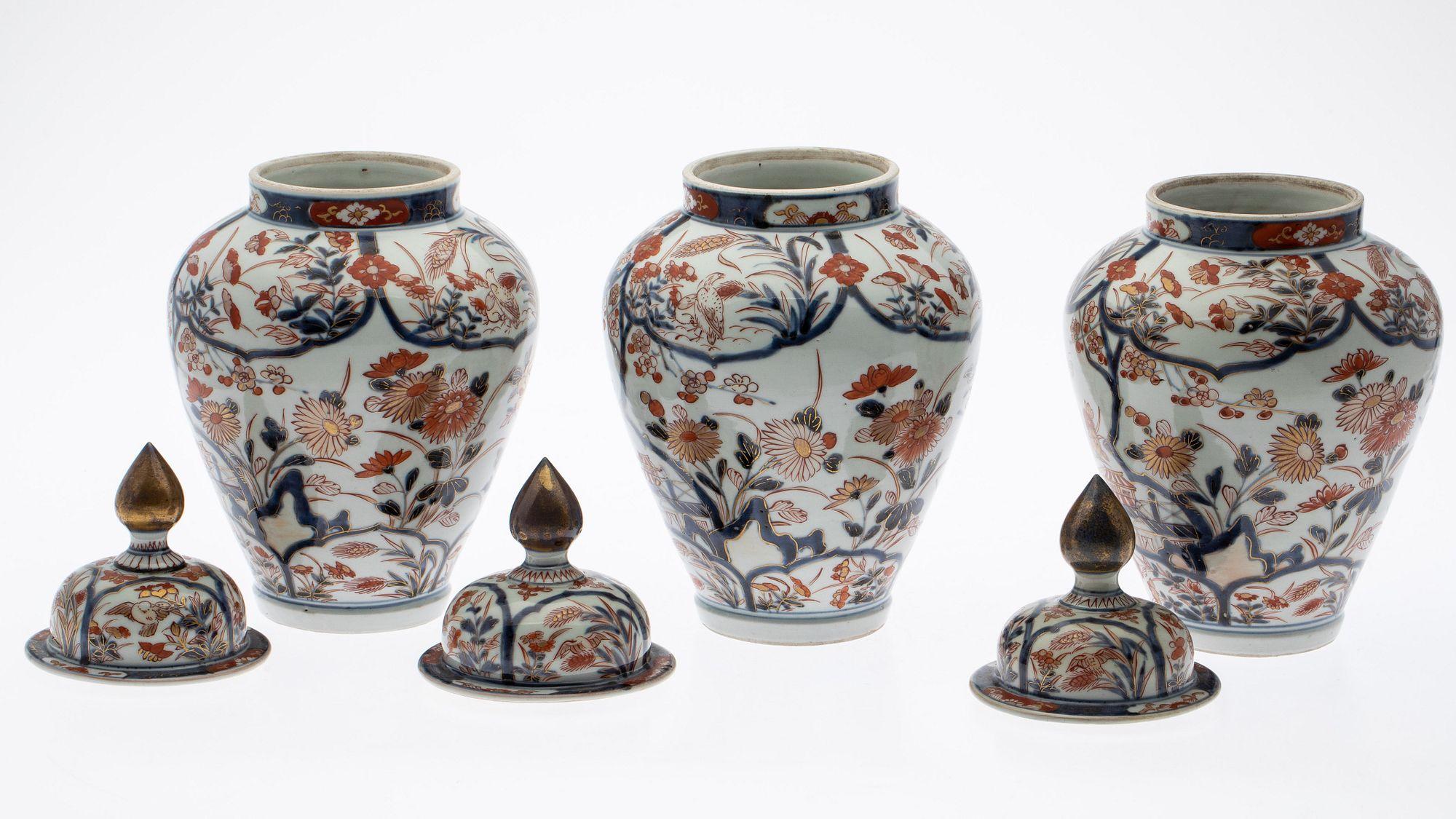 18th century Japanese Hizen ware porcelain garniture in the Imari style, including two vases and three domed jars, dating from the Edo period (1615-1868), painted in underglaze cobalt, red iron oxide and gilt with birds among grass and blossoming