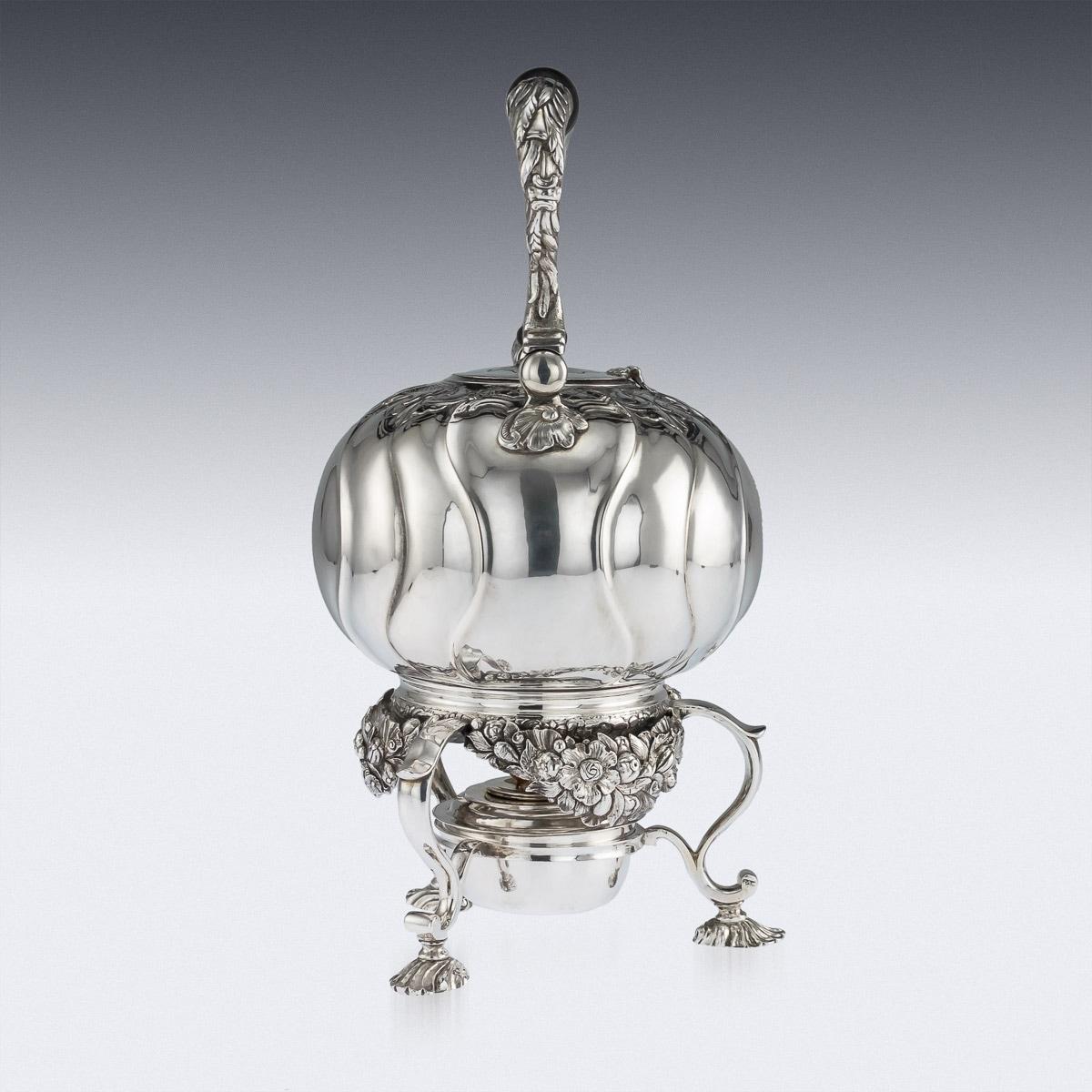 18th Century Imperial Russian silver tea kettle on stand, the bullet shaped body chased with rococo decoration and spiral bands, mounted with a turned wood swing handle and knop, the stand applied with cast floral apron, the burner within three