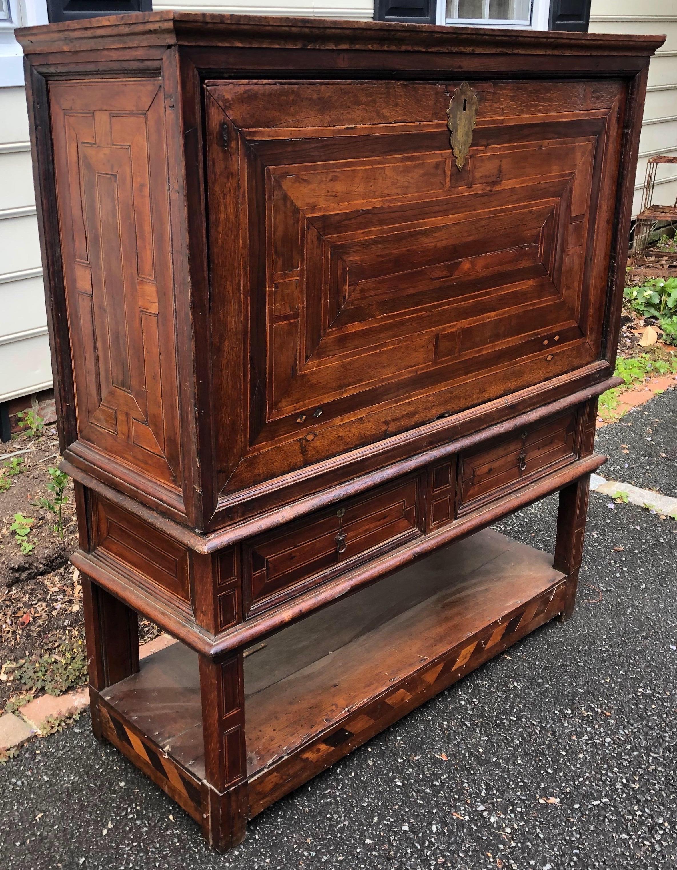 Incredible 18th century walnut Spanish vargueno inlaid with ebony and rosewood decorative panels. The fall front desk consists of wrought iron hinges and drawers with brass pulls- all resting on a stand with two drawers and bottom shelf. There are 2